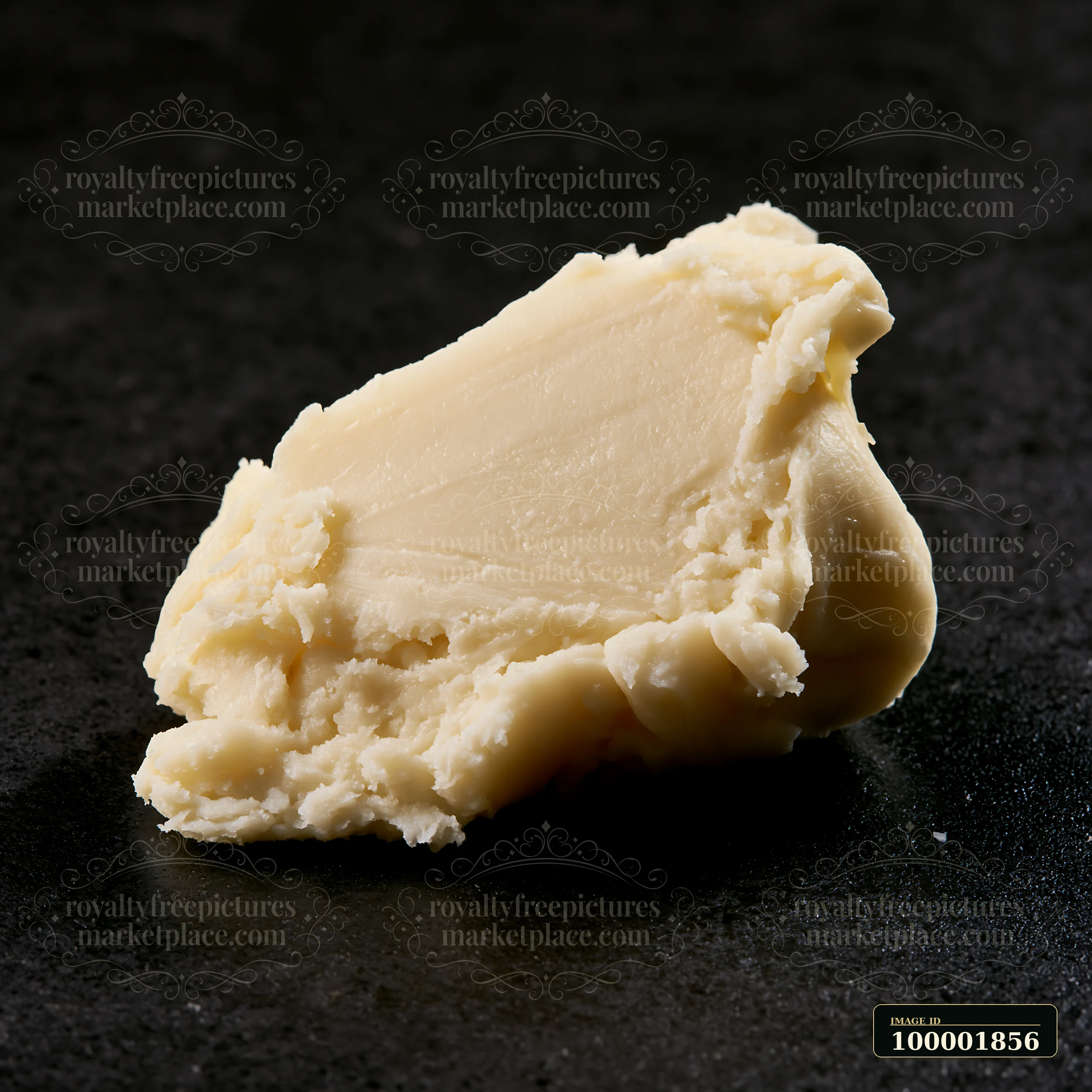 A creamy substance is placed on a dark surface, showcasing its matte texture and consistency.
