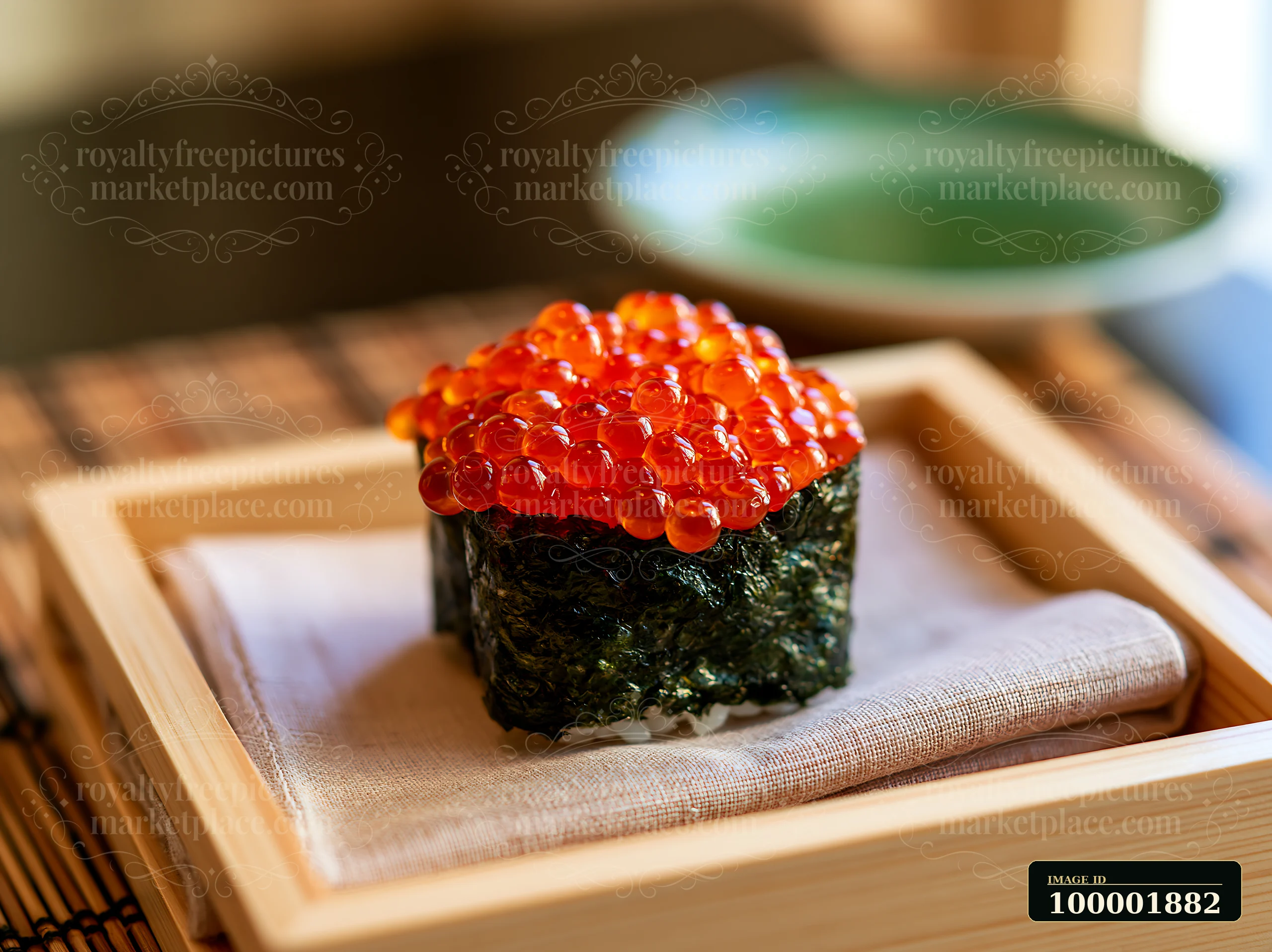 Bright orange ikura salmon roe sushi sits on a bamboo tray with a cloth.