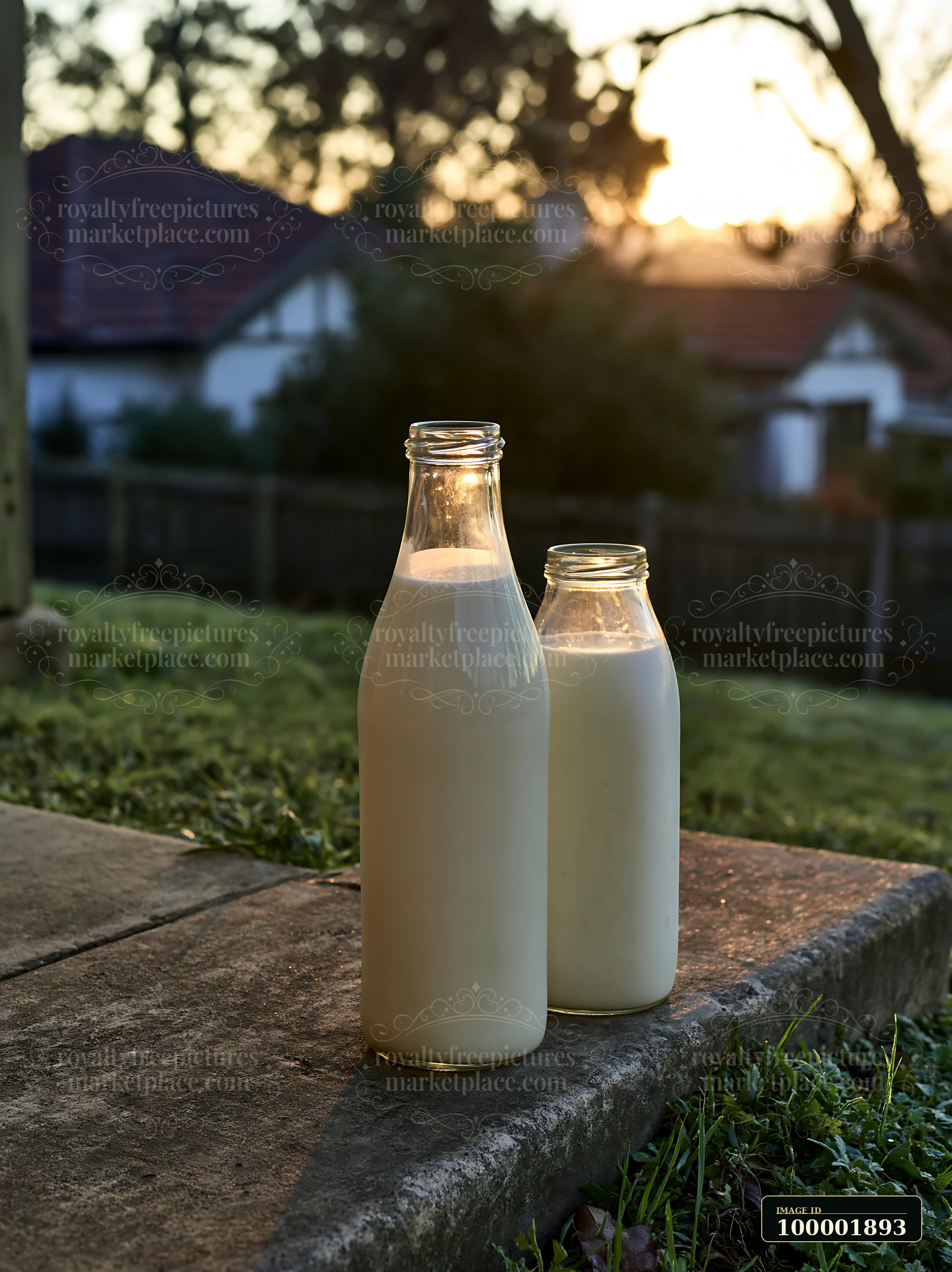 Two glass milk bottles sit on a doorstep as the sun rises.