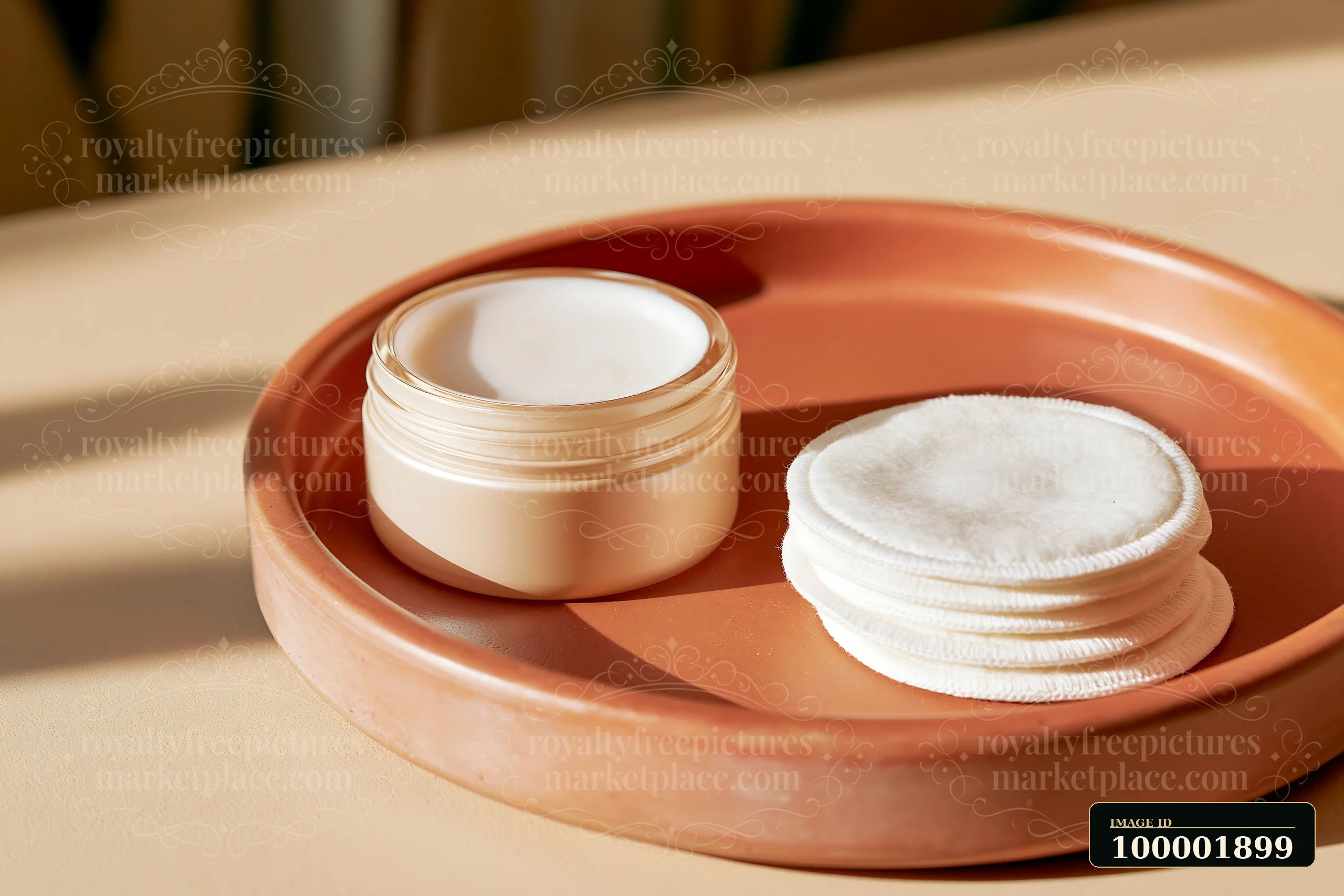 A cream dose is placed beside a stack of cotton pads on a clay plate set on a light surface.