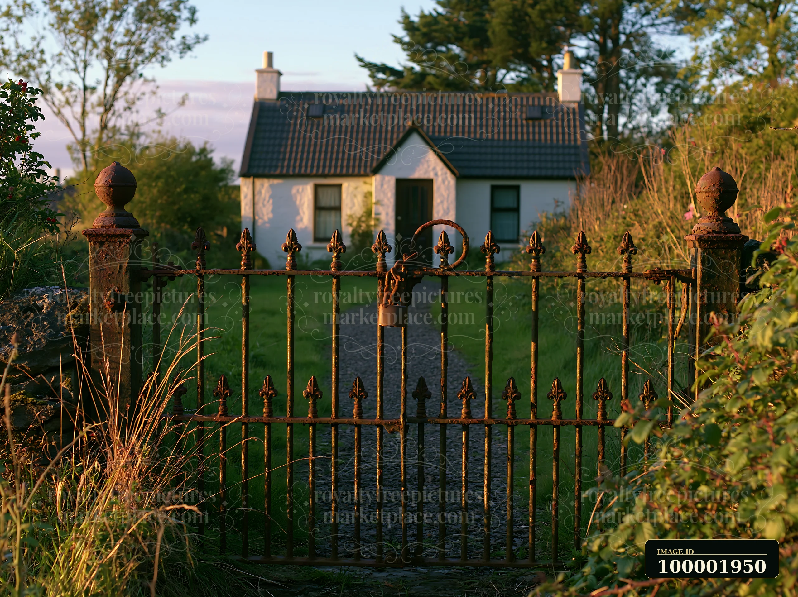 A rustic gate frames a rural cottage with a path leading to the entrance, set among tall grass and trees.