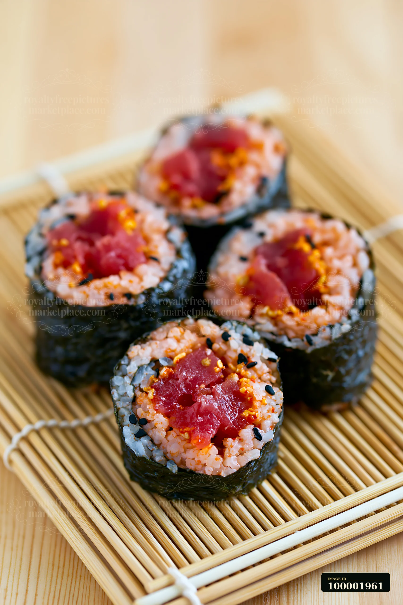 A close view of a spicy tuna roll placed on a bamboo mat.
