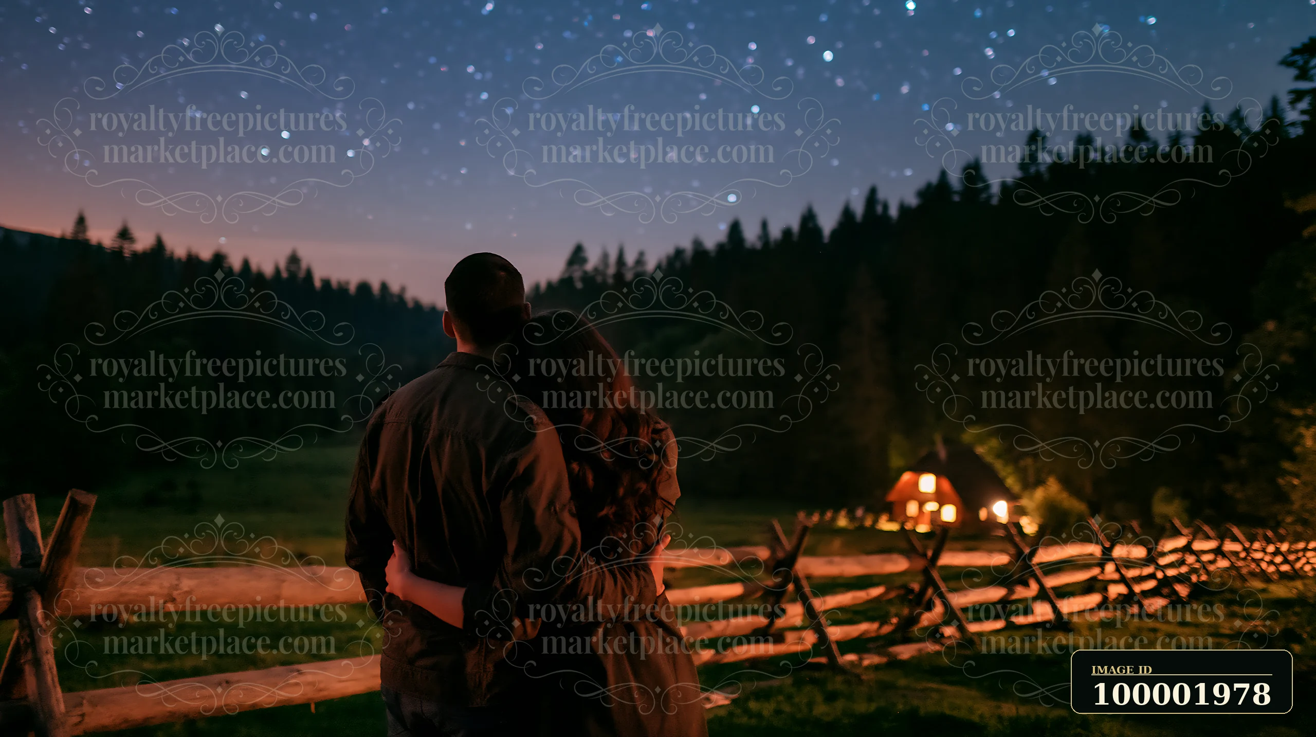 A couple under stars in a pine forest stands close together, surrounded by a wooden fence and a glowing cabin in the background.