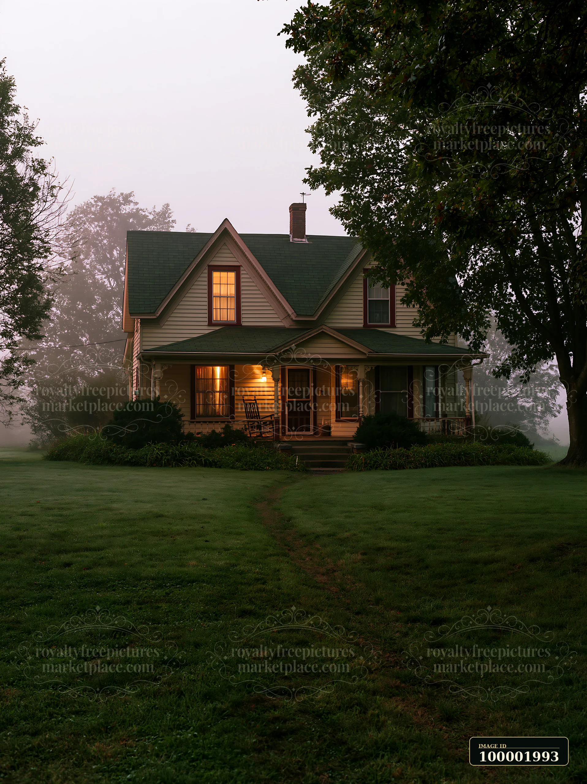 A rural farmhouse in morning fog stands quietly amidst trees and grass.