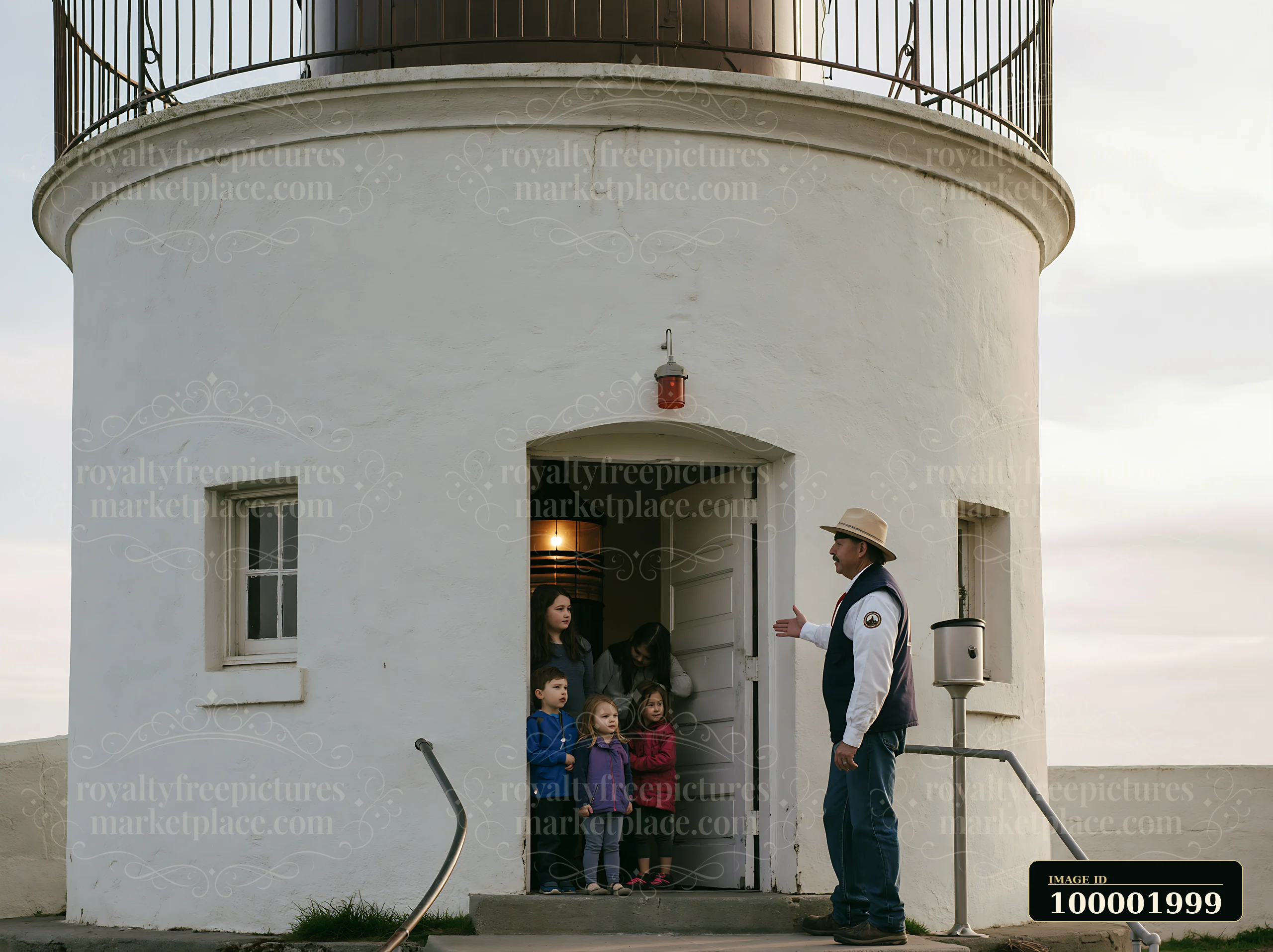 A group of children and adults stands at the entrance of a lighthouse while a guide shares information about the landmark.