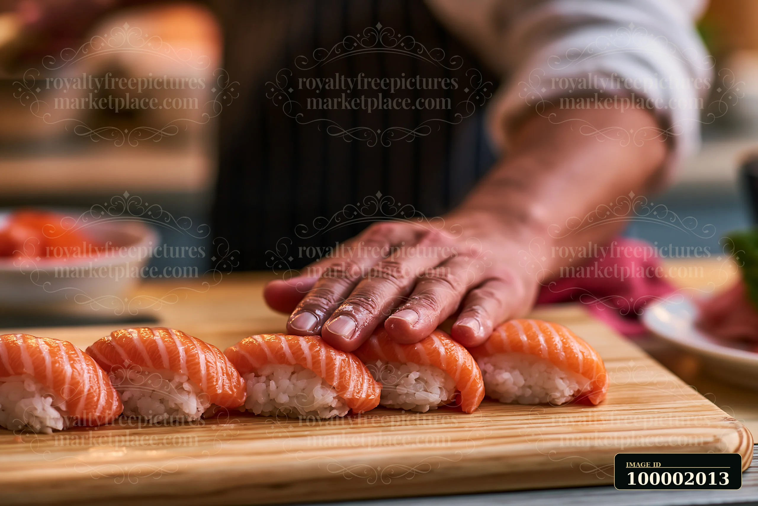 A hand places sushi pieces on a wooden cutting board.
