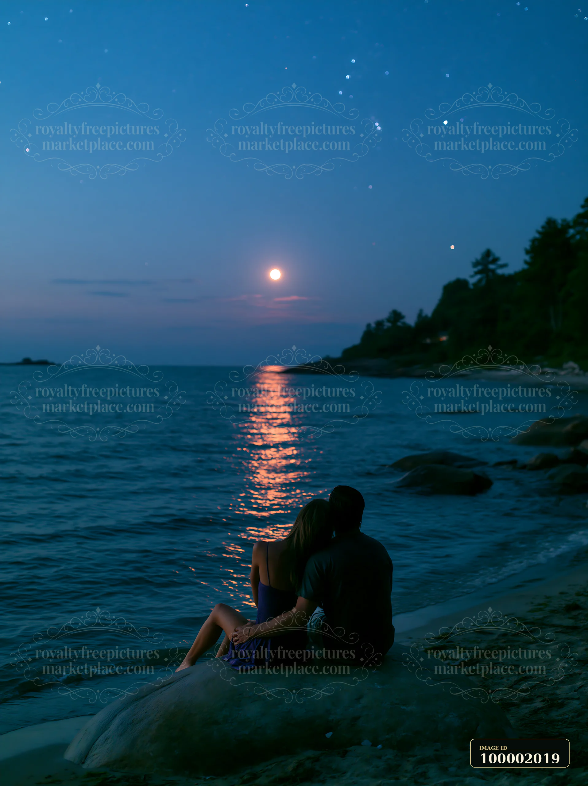 A couple on a beach under stars sits on a rock by the water.