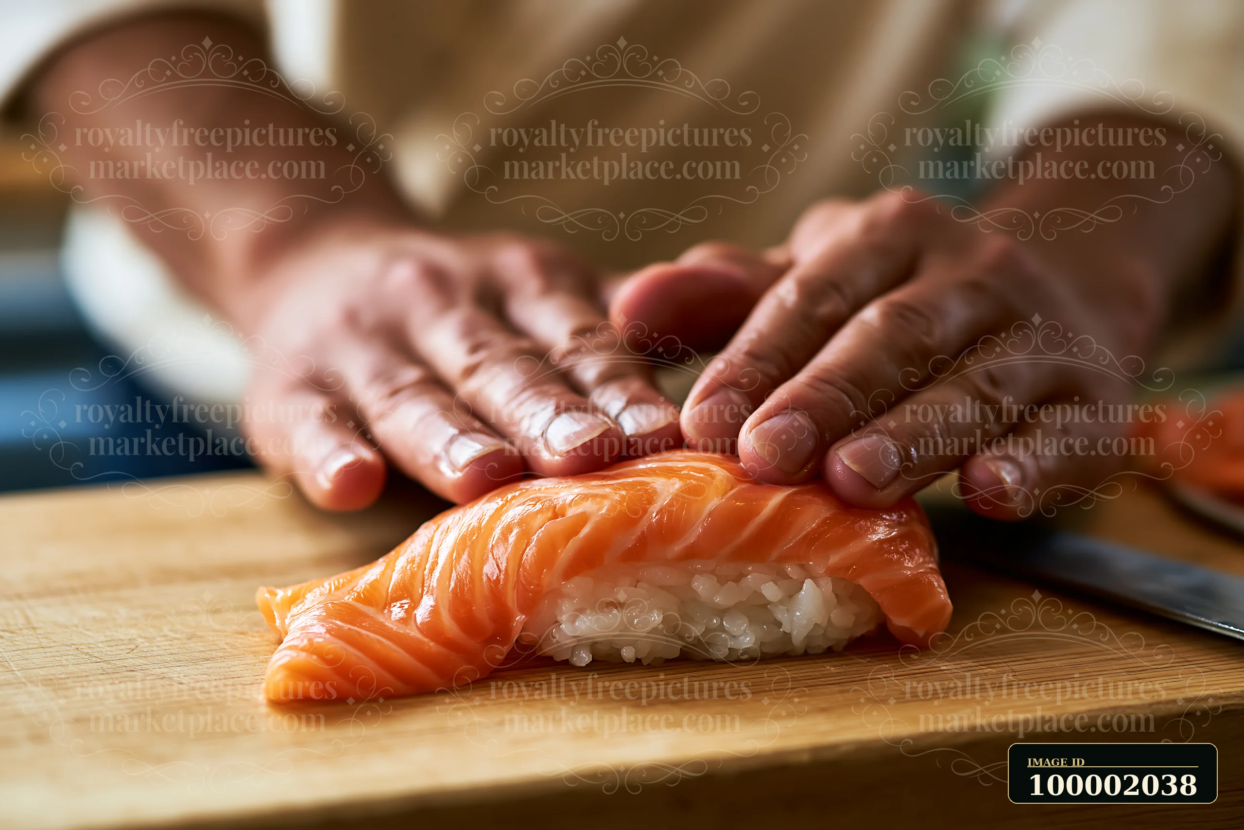 Hands press fresh salmon on rice, creating handmade sushi close-up on a wooden cutting board.