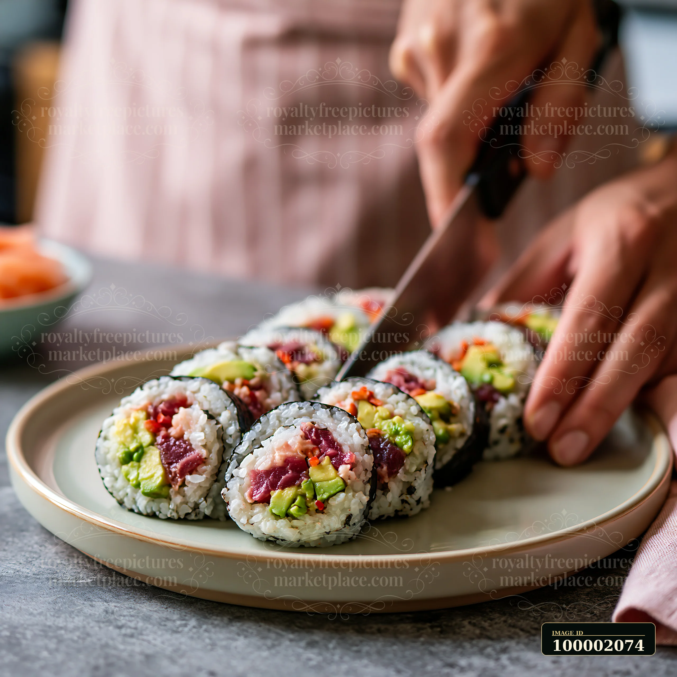 Sushi rolls being cut with a knife show a person preparing food in a kitchen.