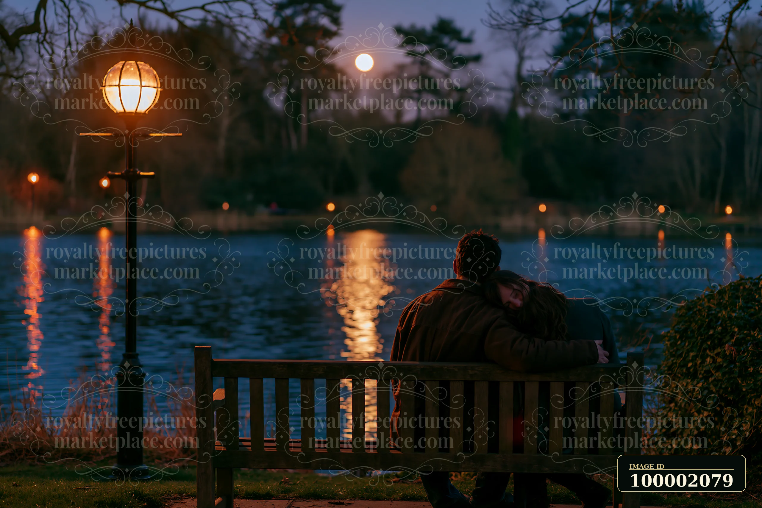 A couple relaxing beside a lake at night, sitting on a bench near a lamp post.