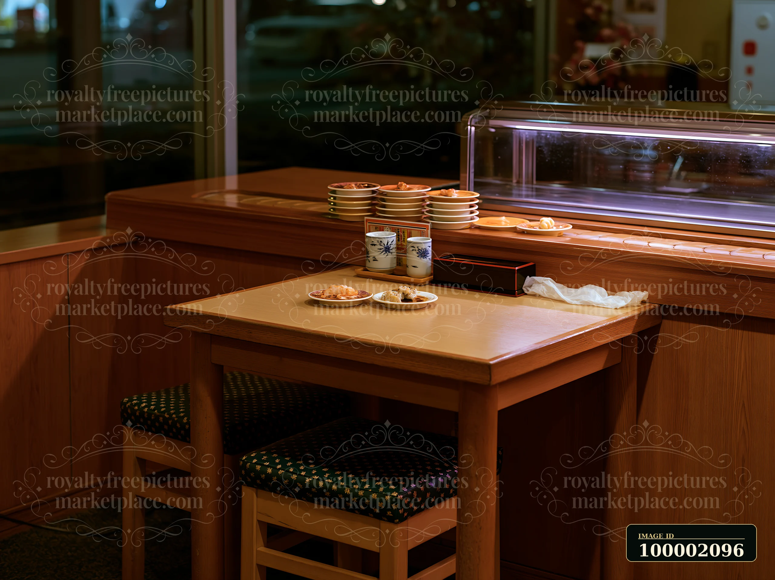 A table with empty plates sits in a sushi conveyor belt restaurant, showcasing a quiet dining area in the evening.