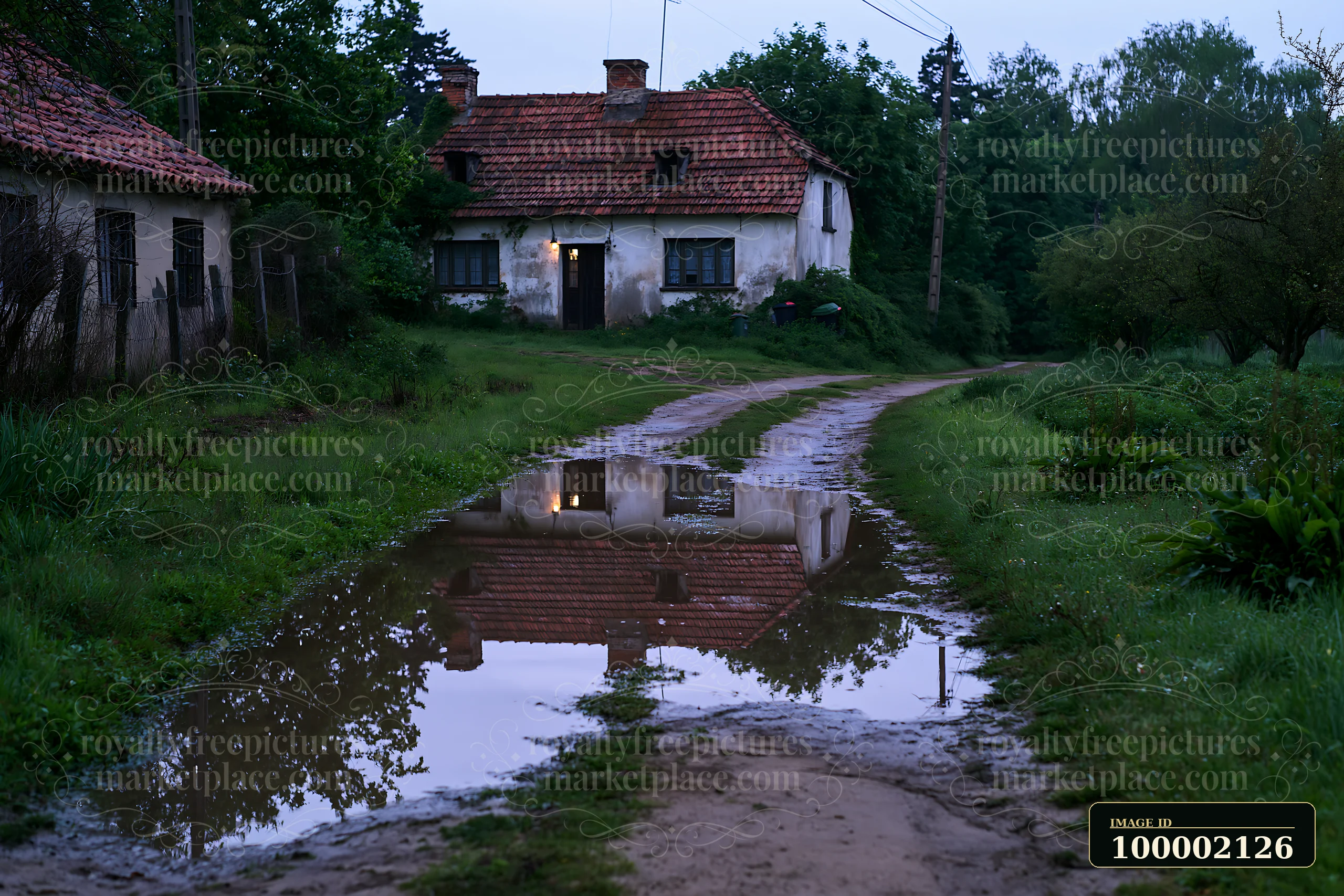 A weathered cottage stands beside a muddy road after rain.