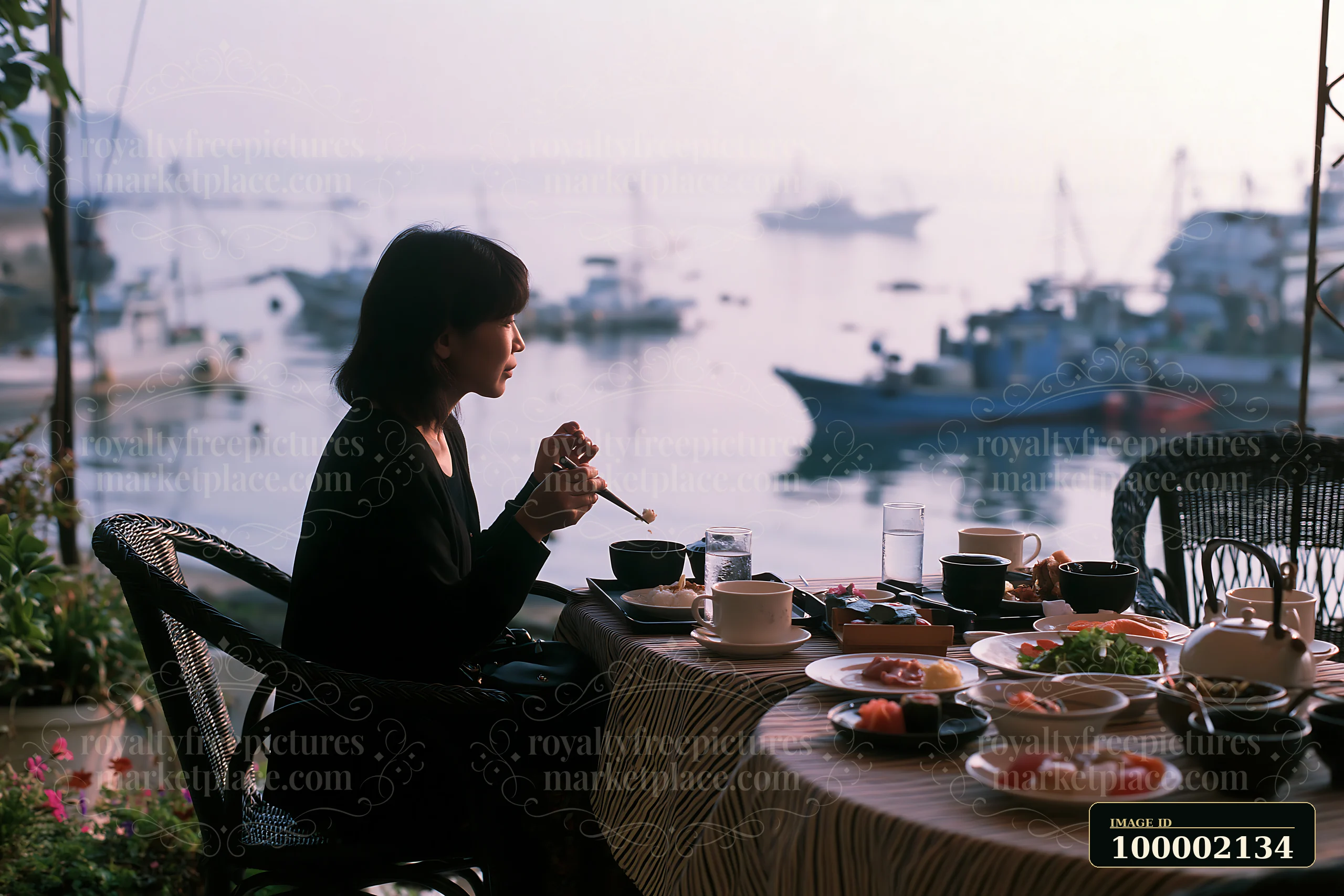 A woman enjoys a traditional sushi breakfast in Japan, seated by the water with boats in the background.