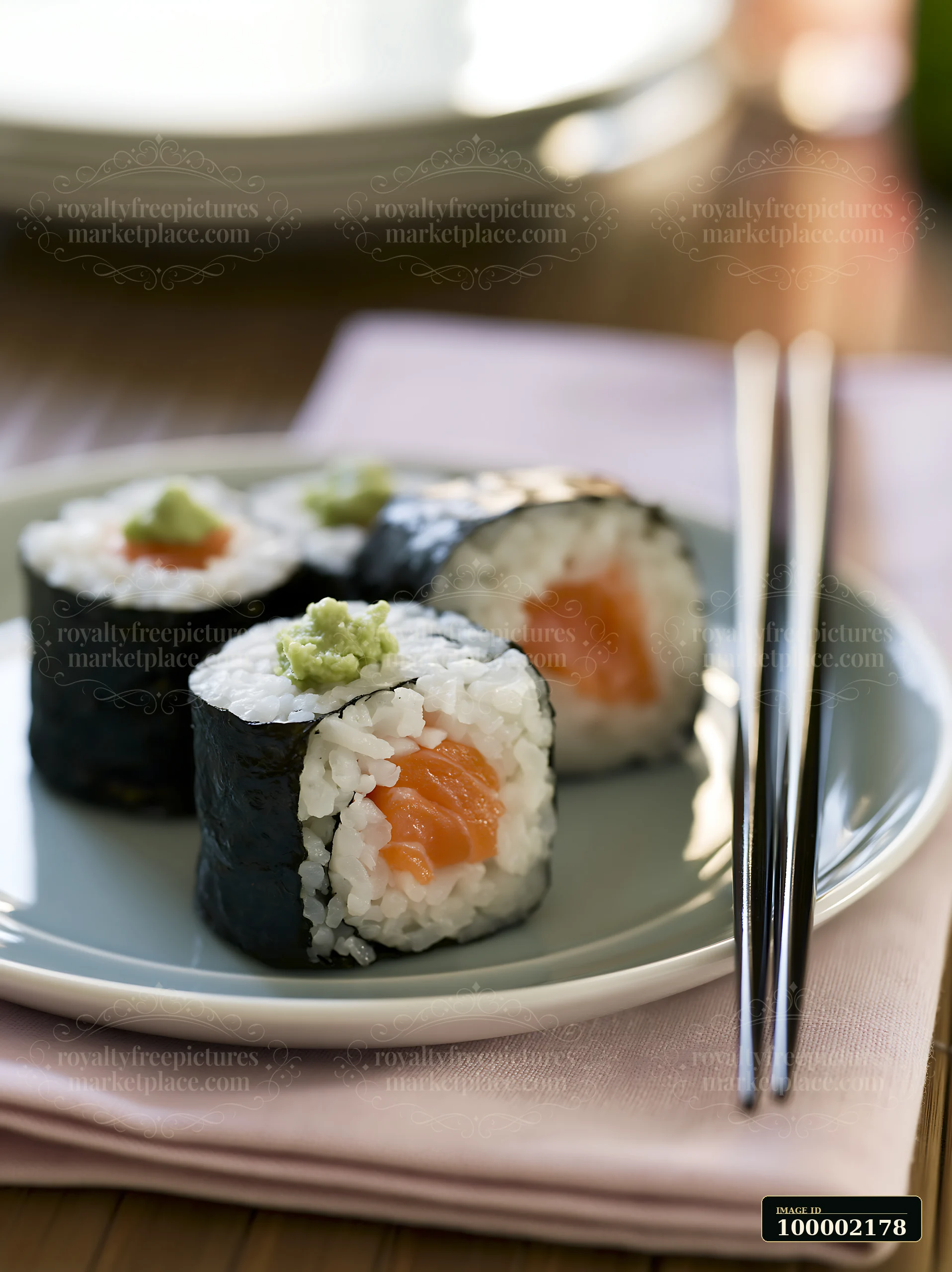 One salmon maki piece with wasabi rests on a plate alongside other sushi pieces.
