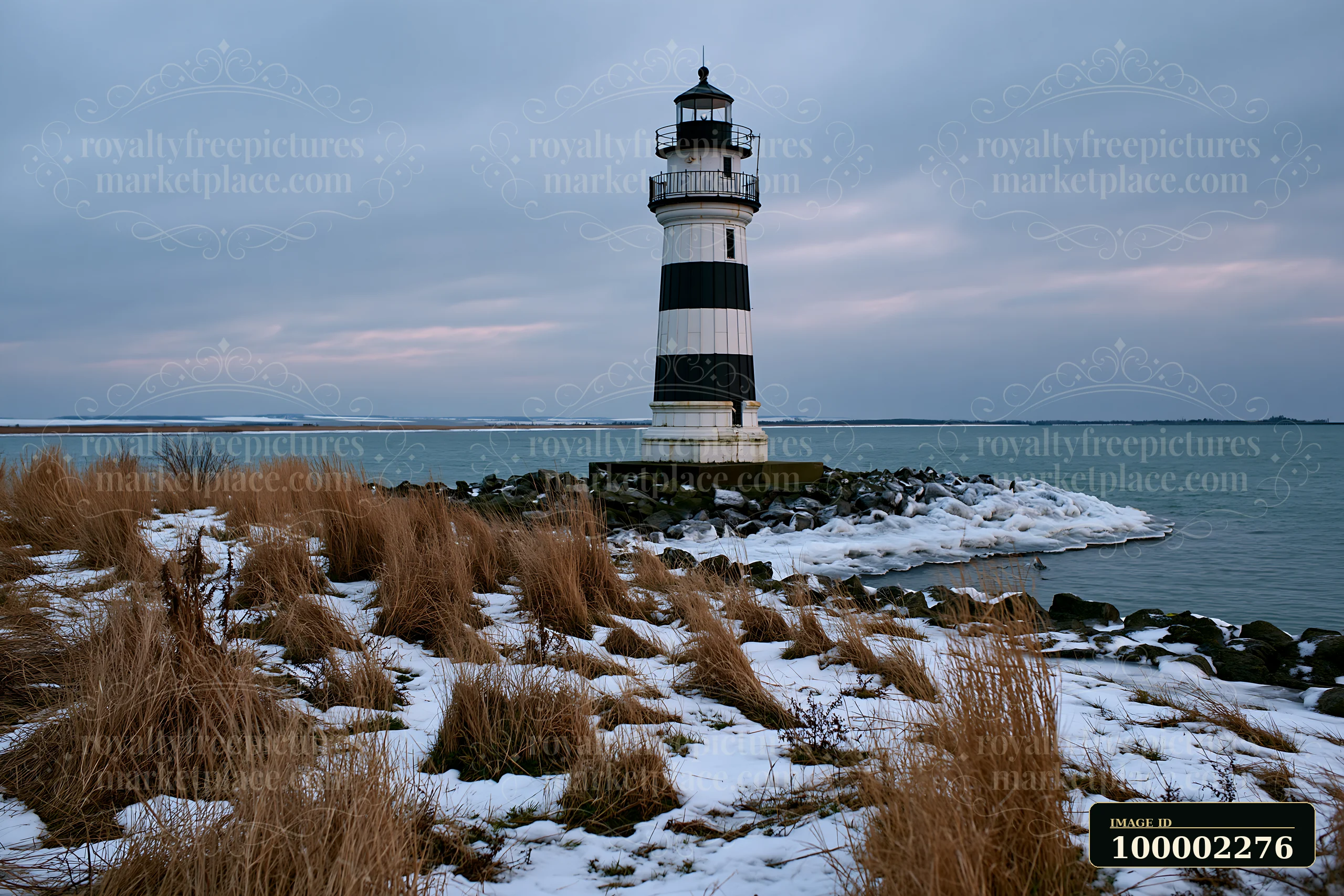 A lighthouse with black and white stripes stands on the shore, surrounded by snow and rocky terrain.