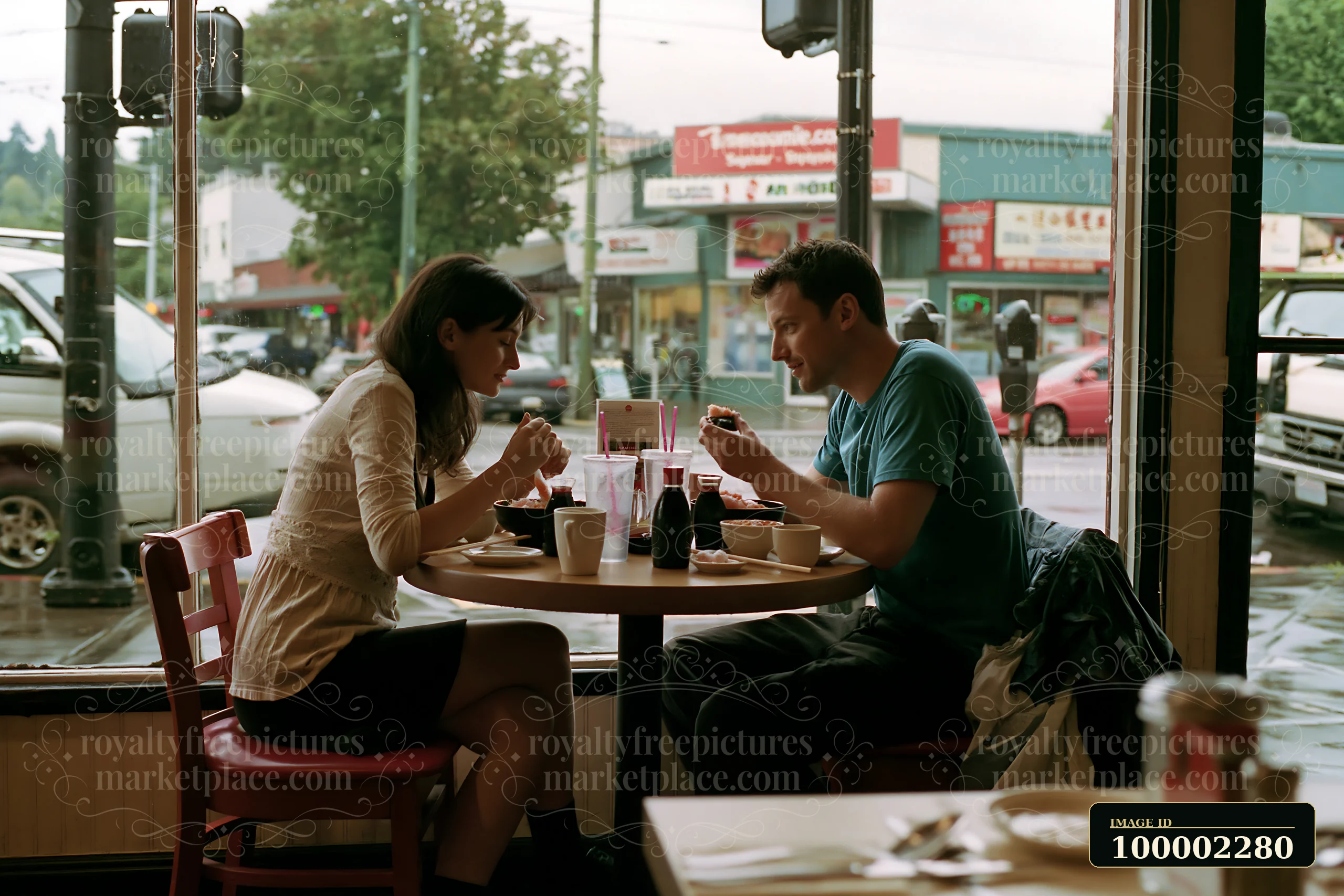 A couple shares a romantic sushi dinner at a restaurant with large windows.