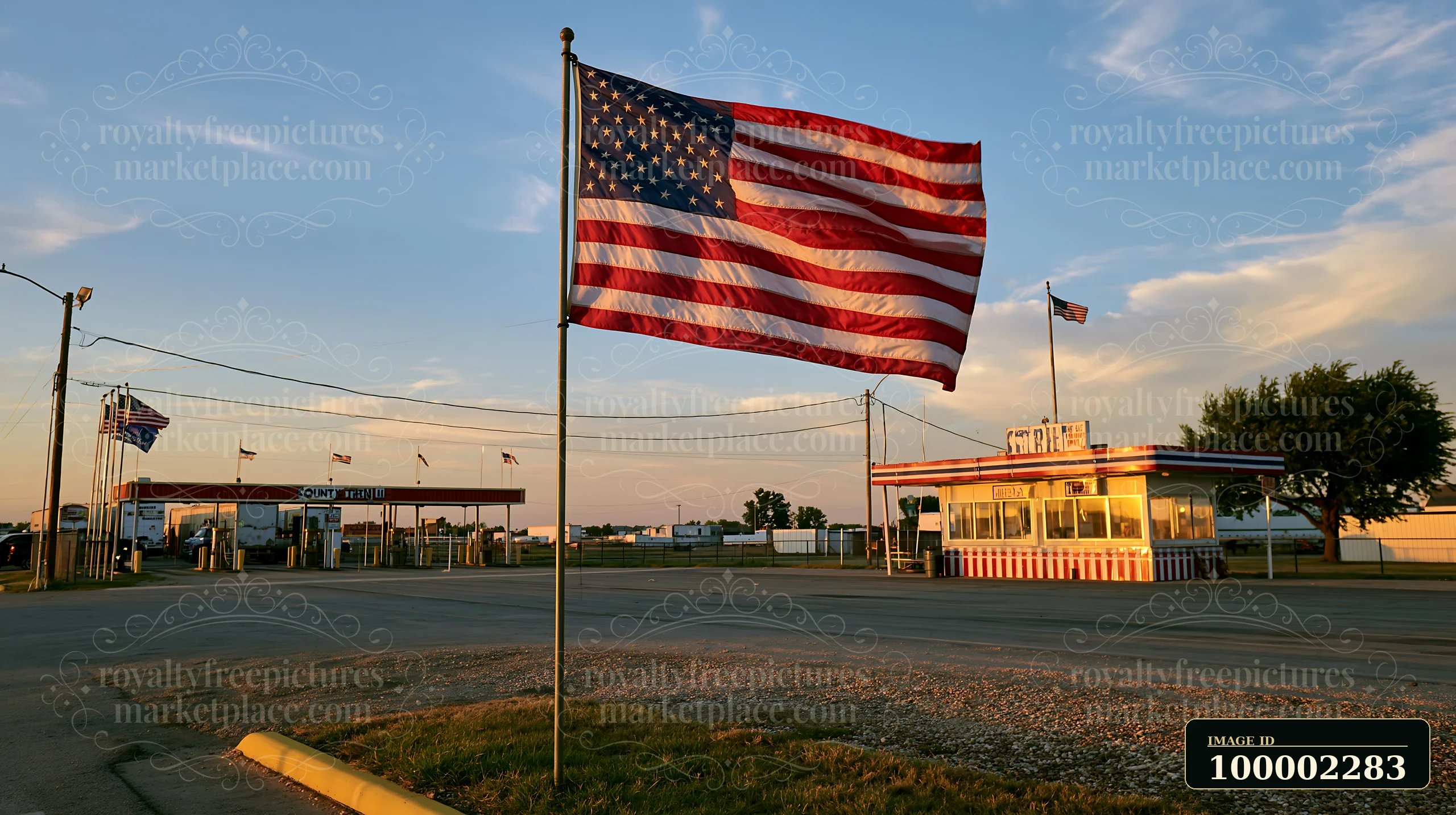 The American flag flying in strong wind stands beside a roadside stand during sunset.