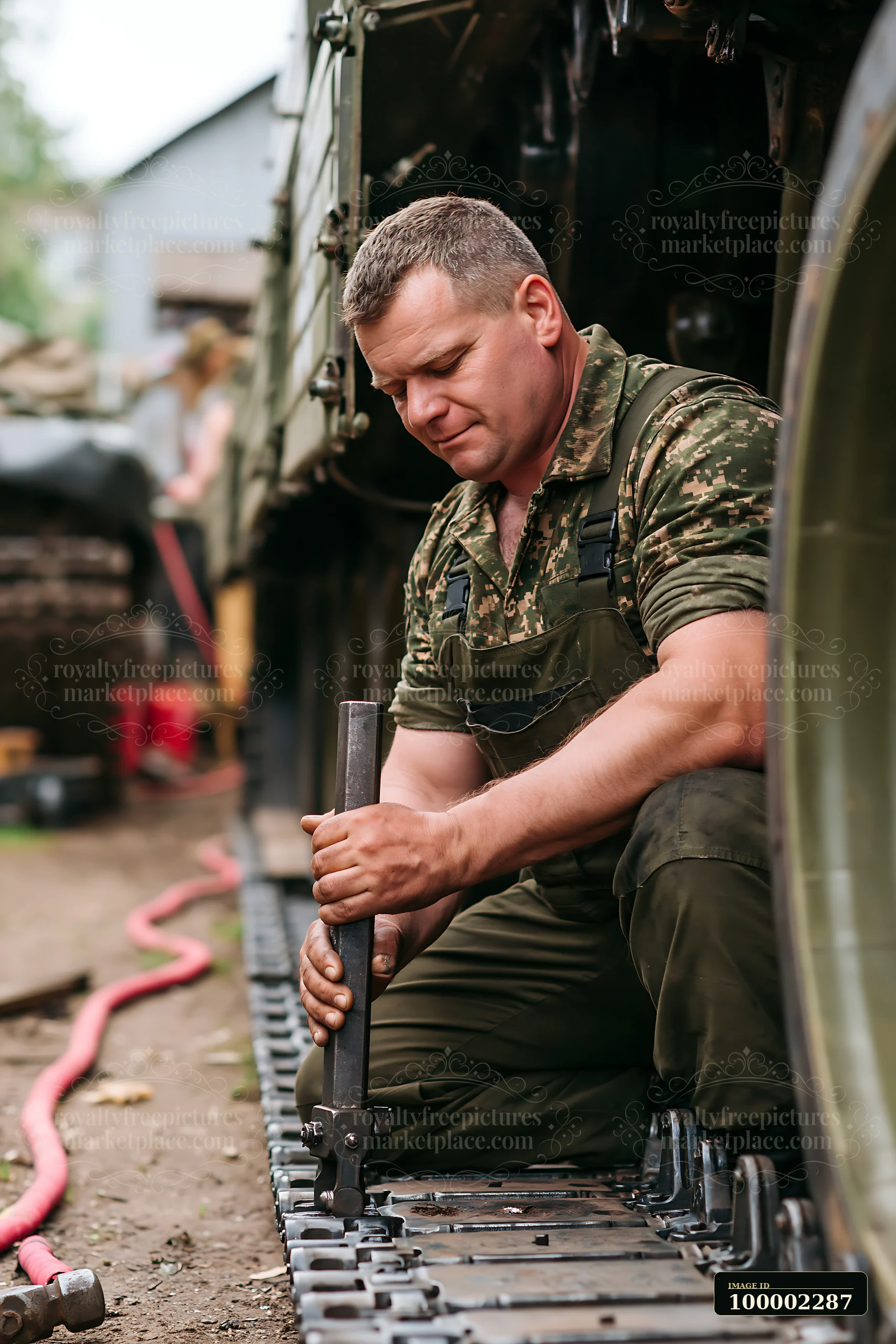 A soldier performs maintenance on a panzer tank using various tools in an outdoor setting.