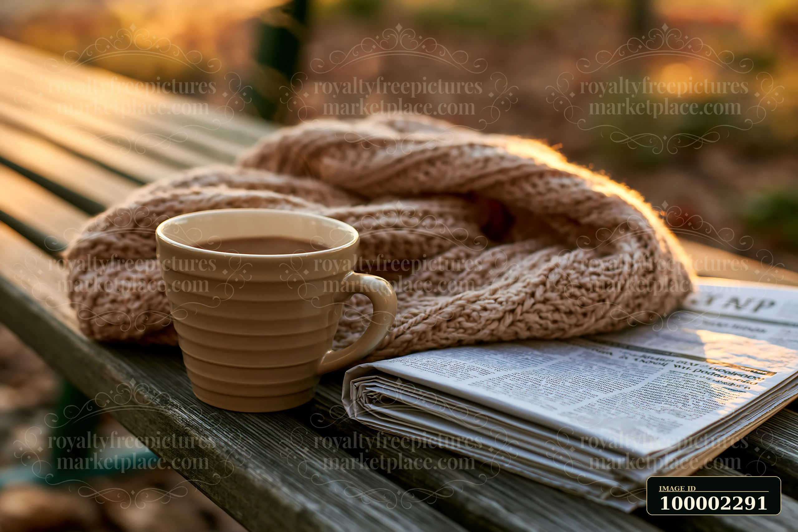 A cup of coffee sits next to a newspaper on a wooden table covered with a knitted blanket, surrounded by autumn leaves in a park during the day.
