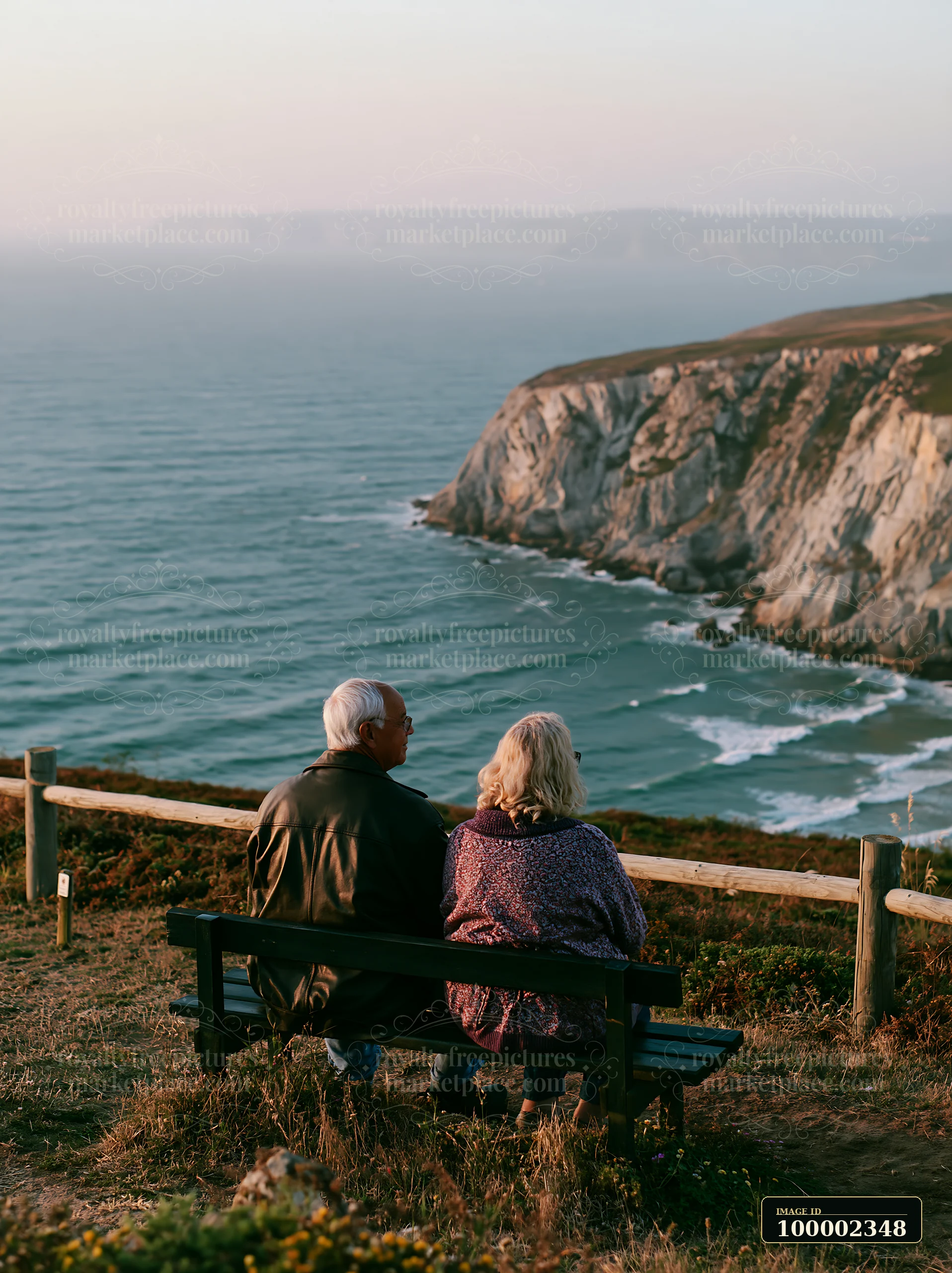 A couple sits on a bench enjoying the view of the coastline with sustainable tourism sign.