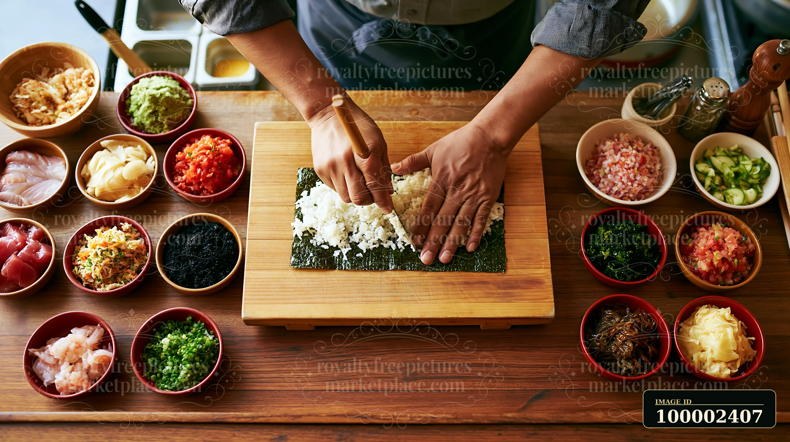 A chef preparing sushi at restaurant counter uses rice and seaweed to create sushi rolls.