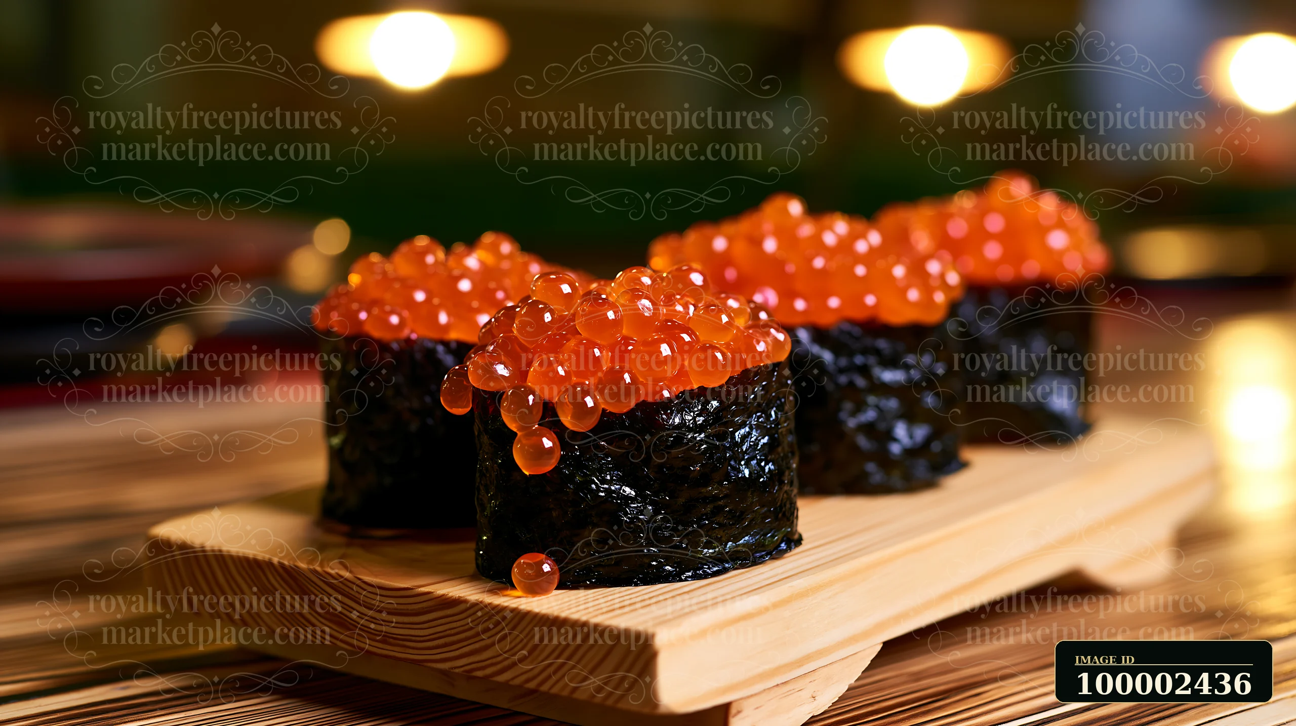 Four pieces of sushi topped with bright orange ikura salmon roe sit on a wooden platter.
