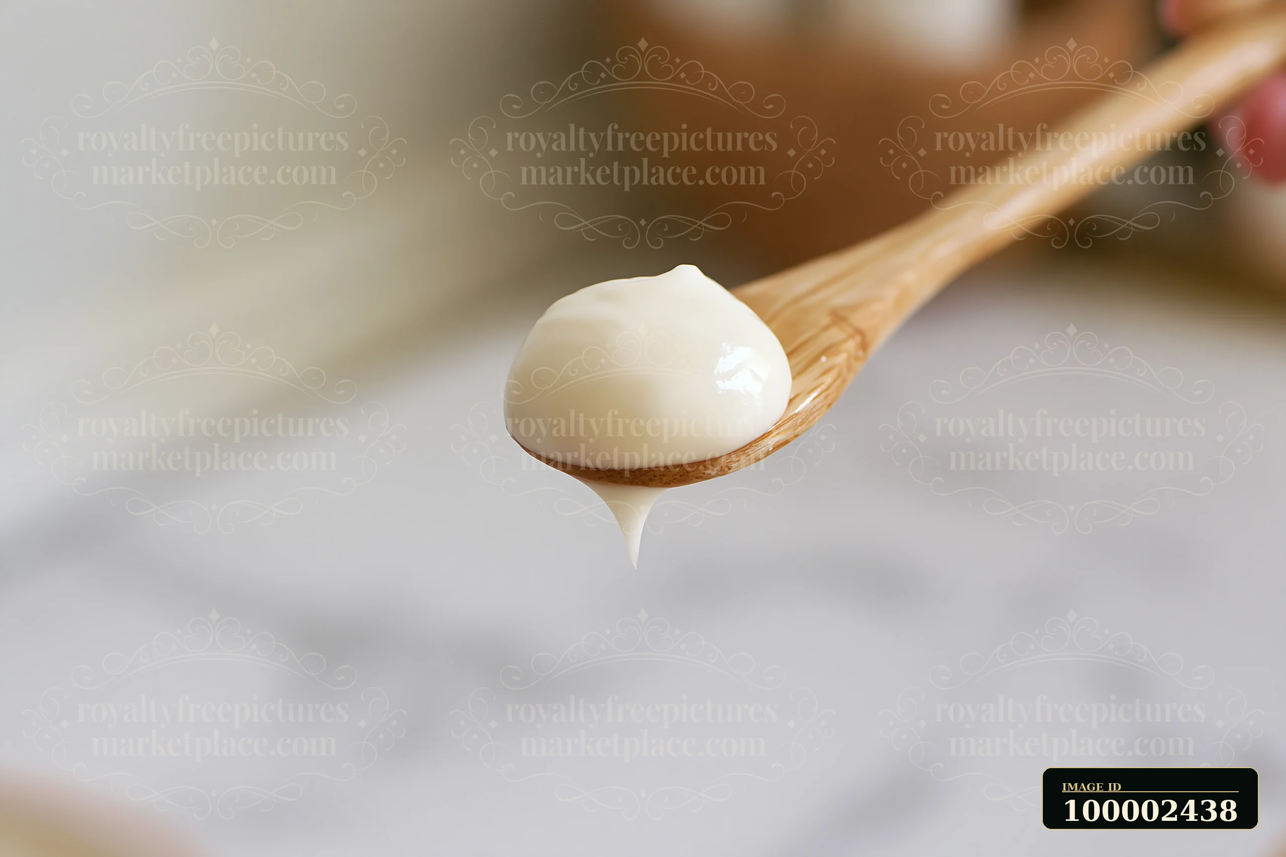A wooden spoon holds a cream dose with matte texture, dripping slightly.