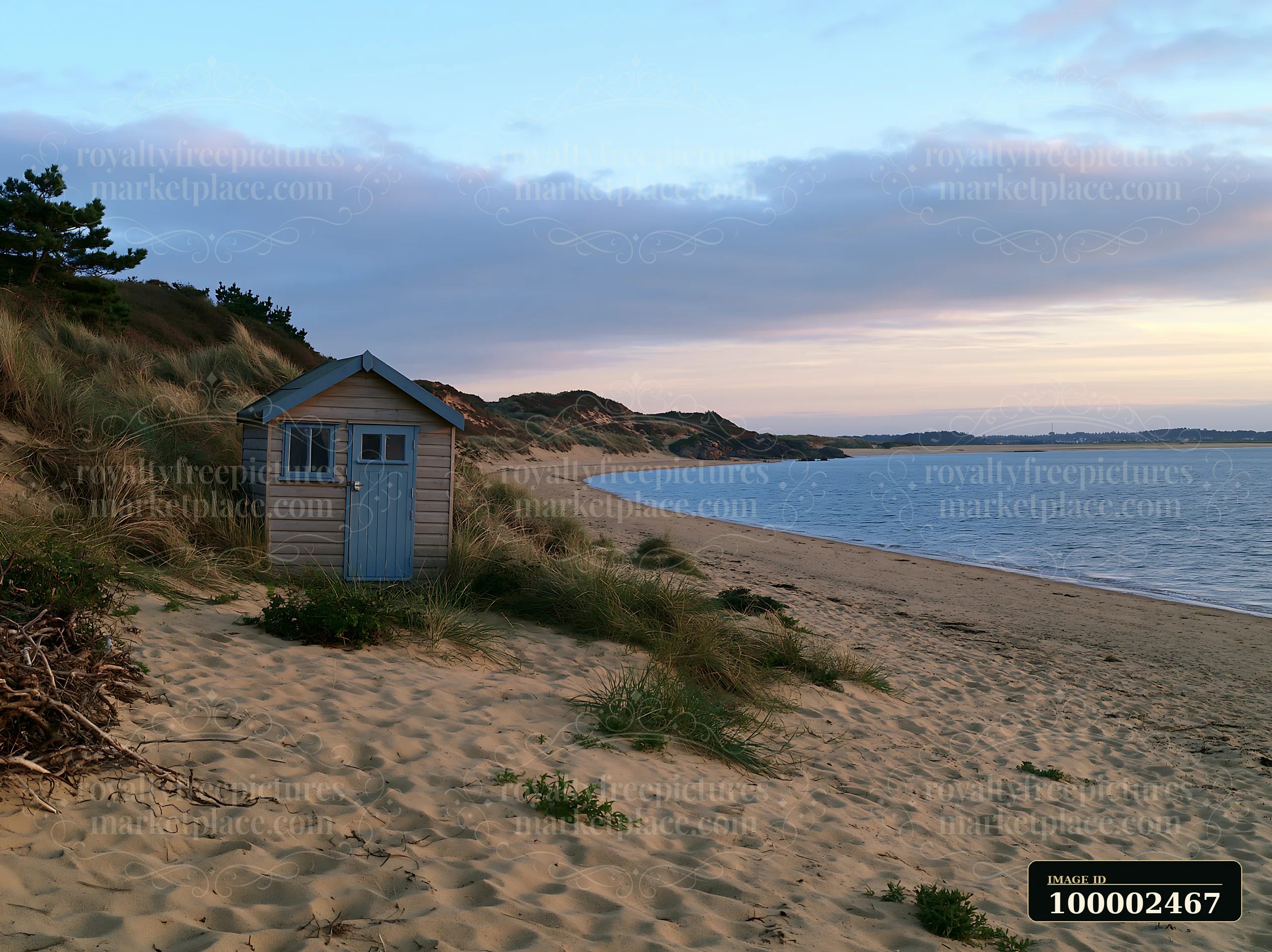 A small beach hut sits along the coastline with sheltered bay, surrounded by sand dunes and vegetation.