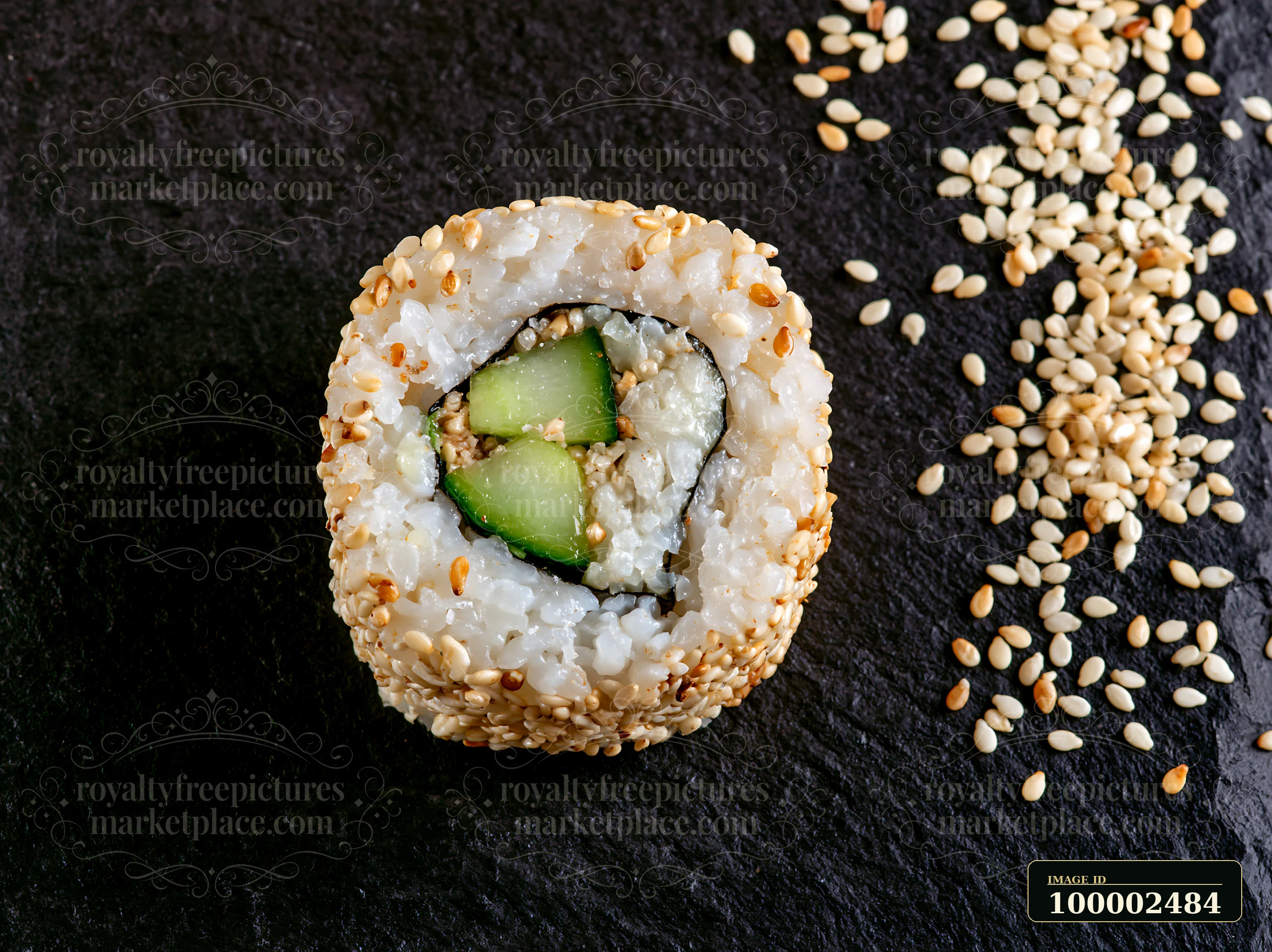 A single sushi piece sits on a black slate surface surrounded by scattered sesame seeds.