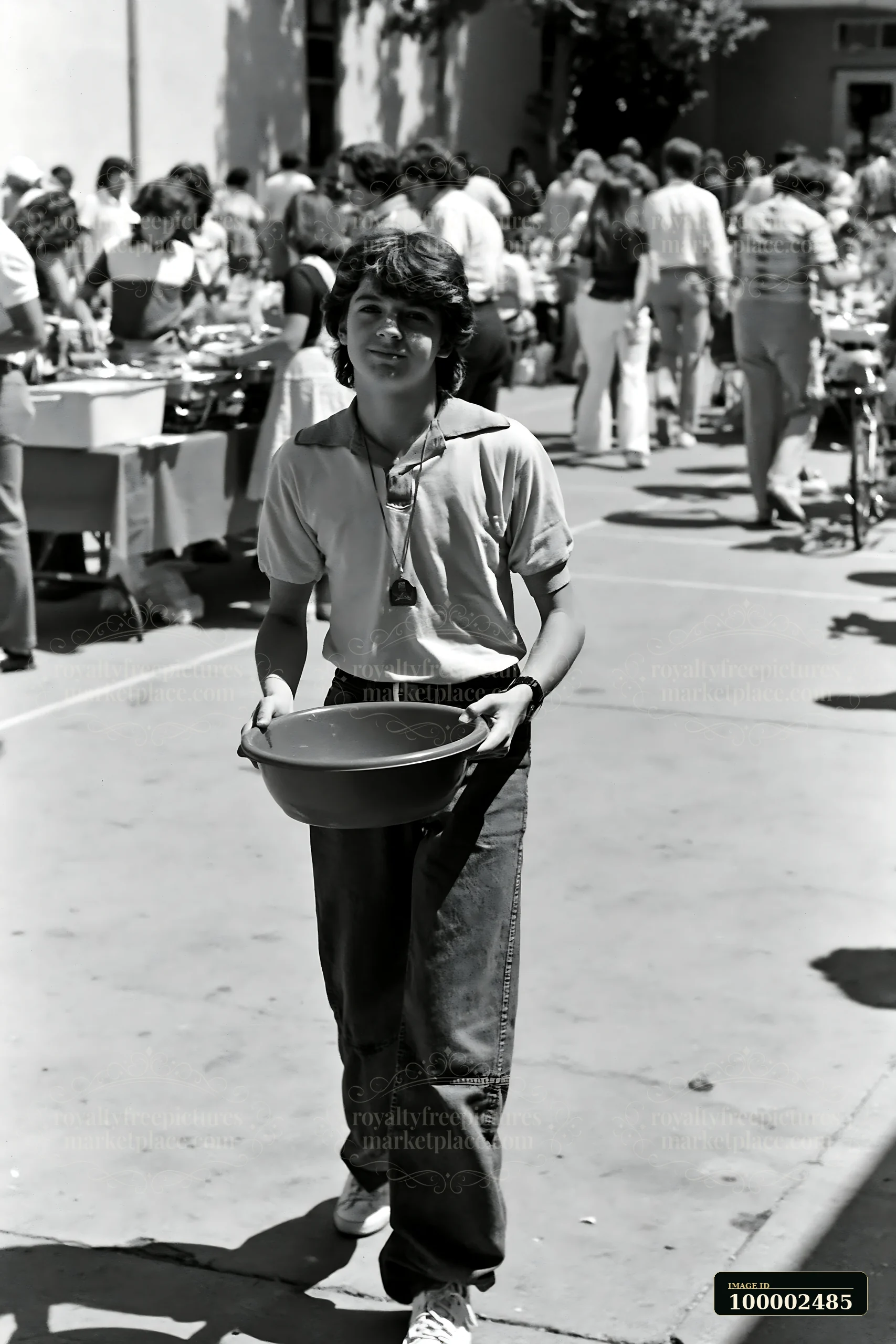 A young person carries a bowl while walking through a bustling community potluck buffet.