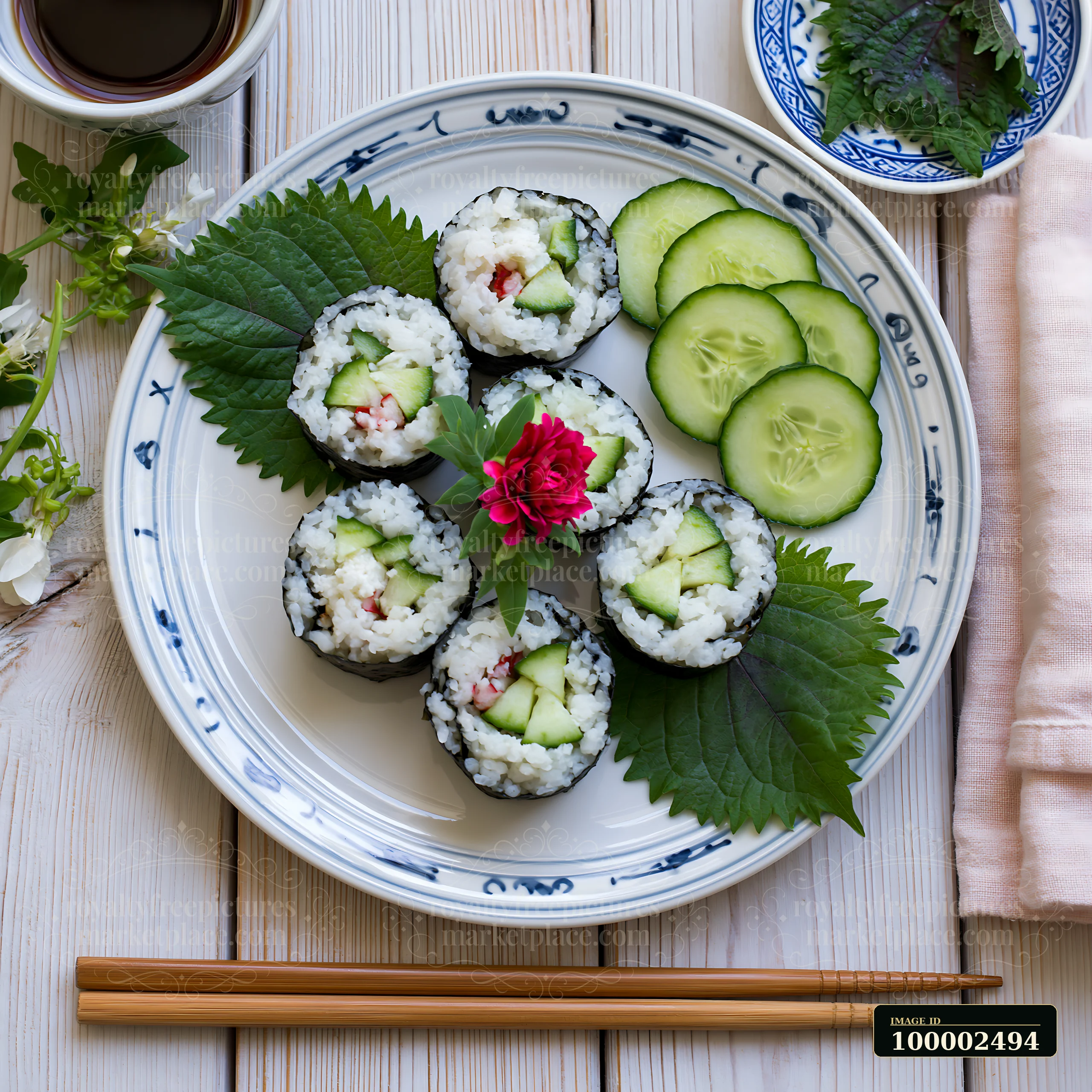Sushi with shiso leaves is arranged beautifully on a plate, accompanied by sliced cucumbers.