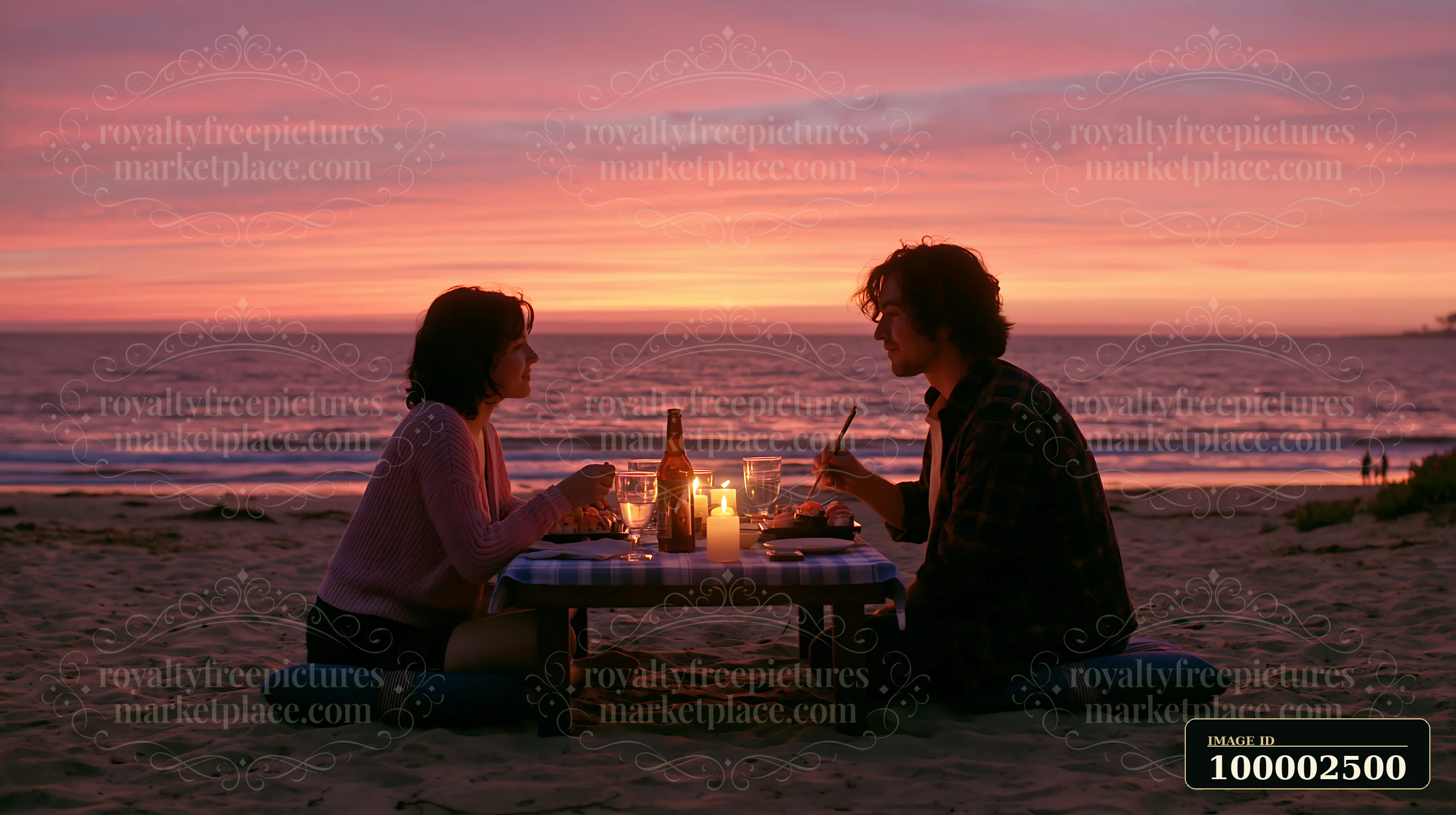 A couple enjoys a romantic sushi dinner on the beach with a beautiful sunset in the background.