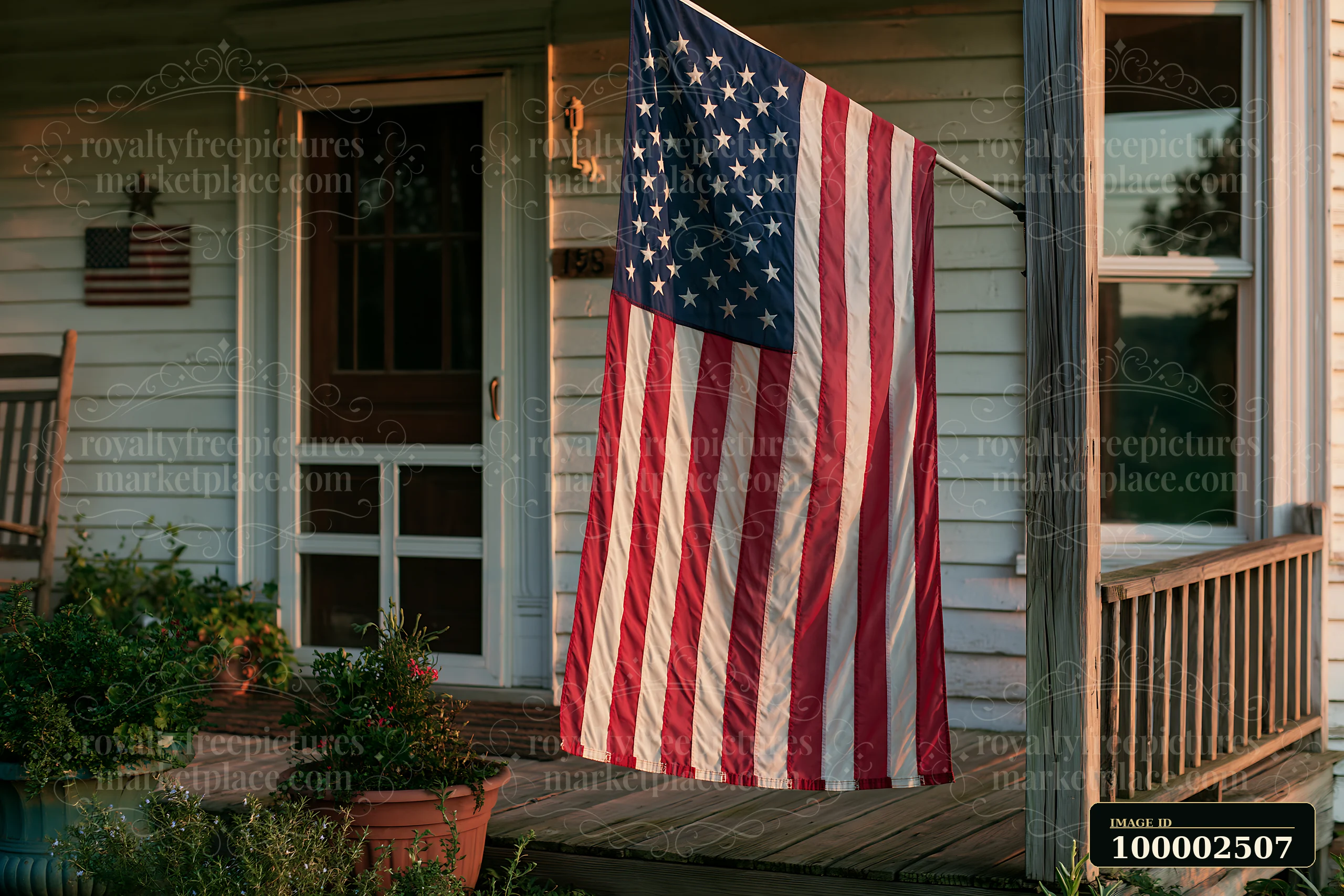 An American flag hanging from a porch sways gently in the breeze.