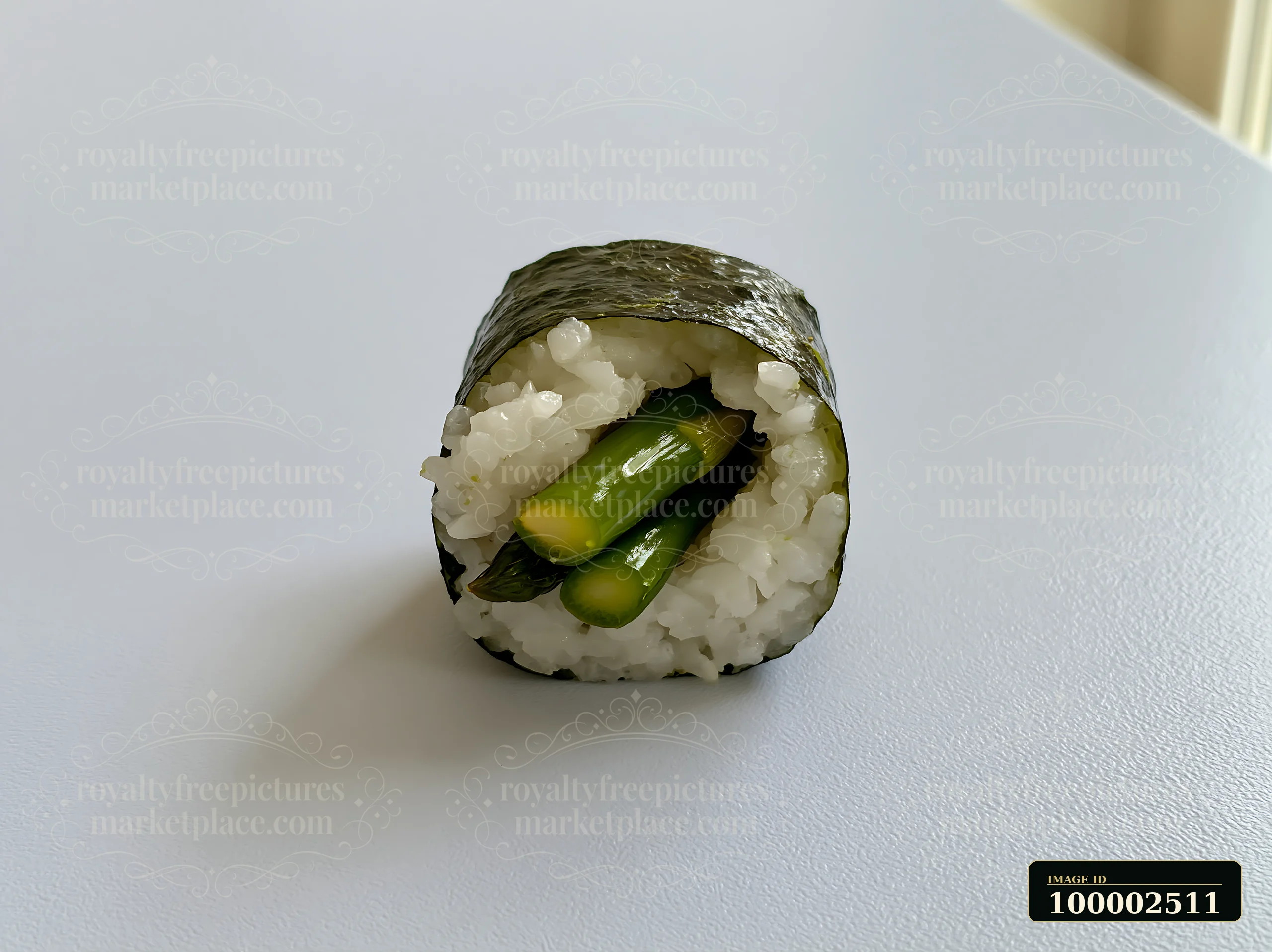 One sushi piece sits on a minimalist table, showcasing a simple design with neat layers of rice and green vegetables.