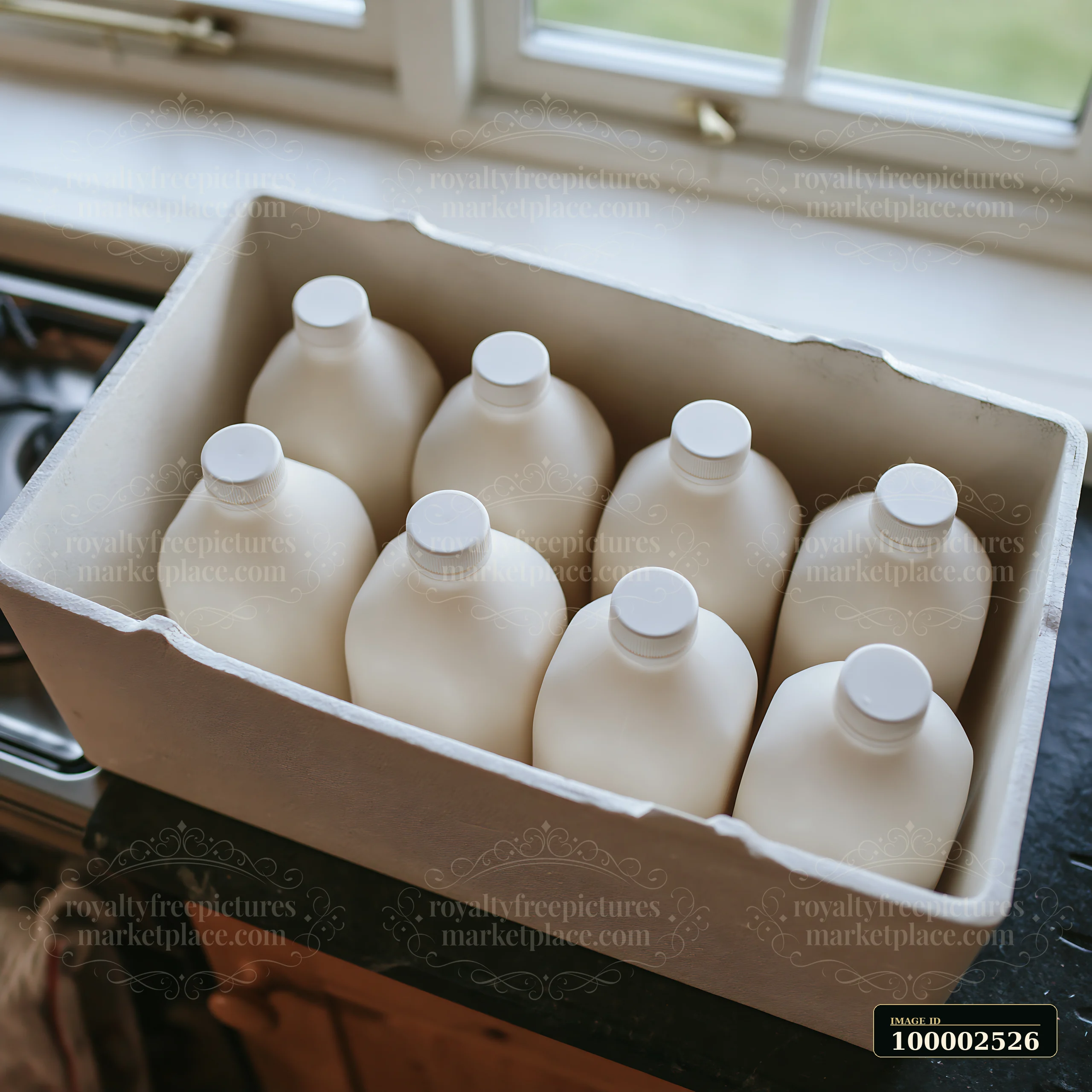 Milk bottles in an insulated delivery box sit neatly organized inside a kitchen.