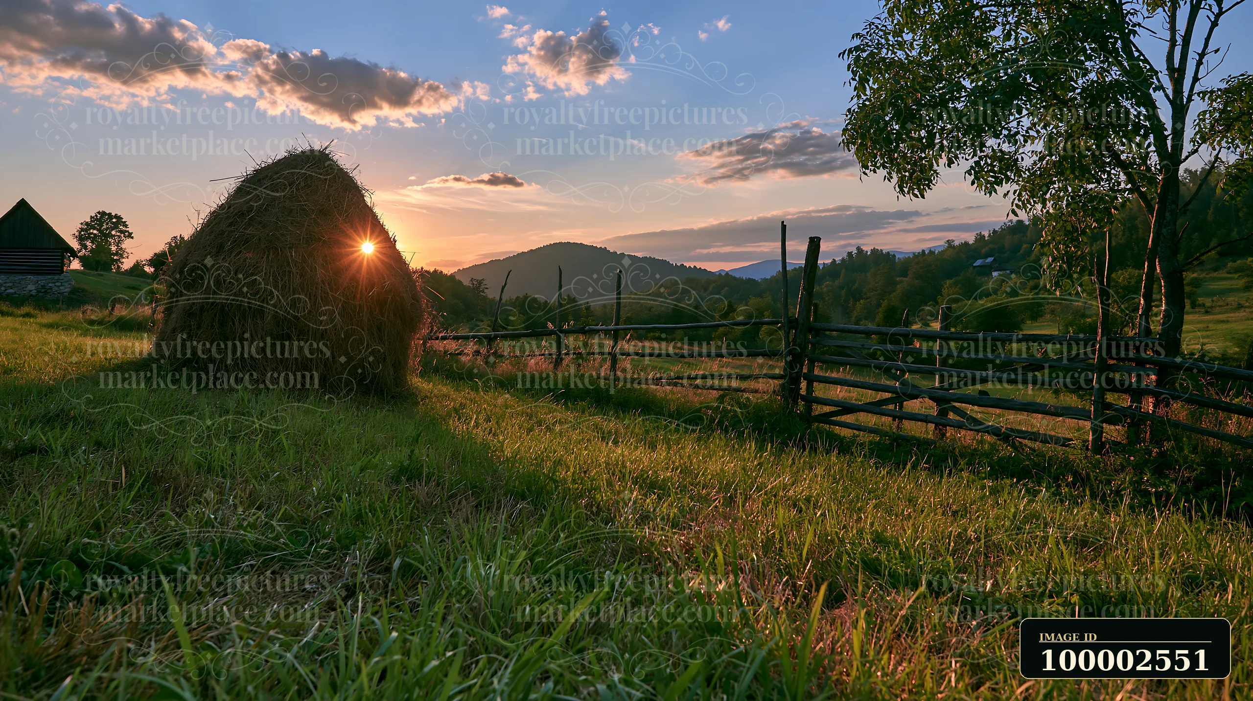 A traditional haystack sits in a meadow as the sun sets behind rolling hills.
