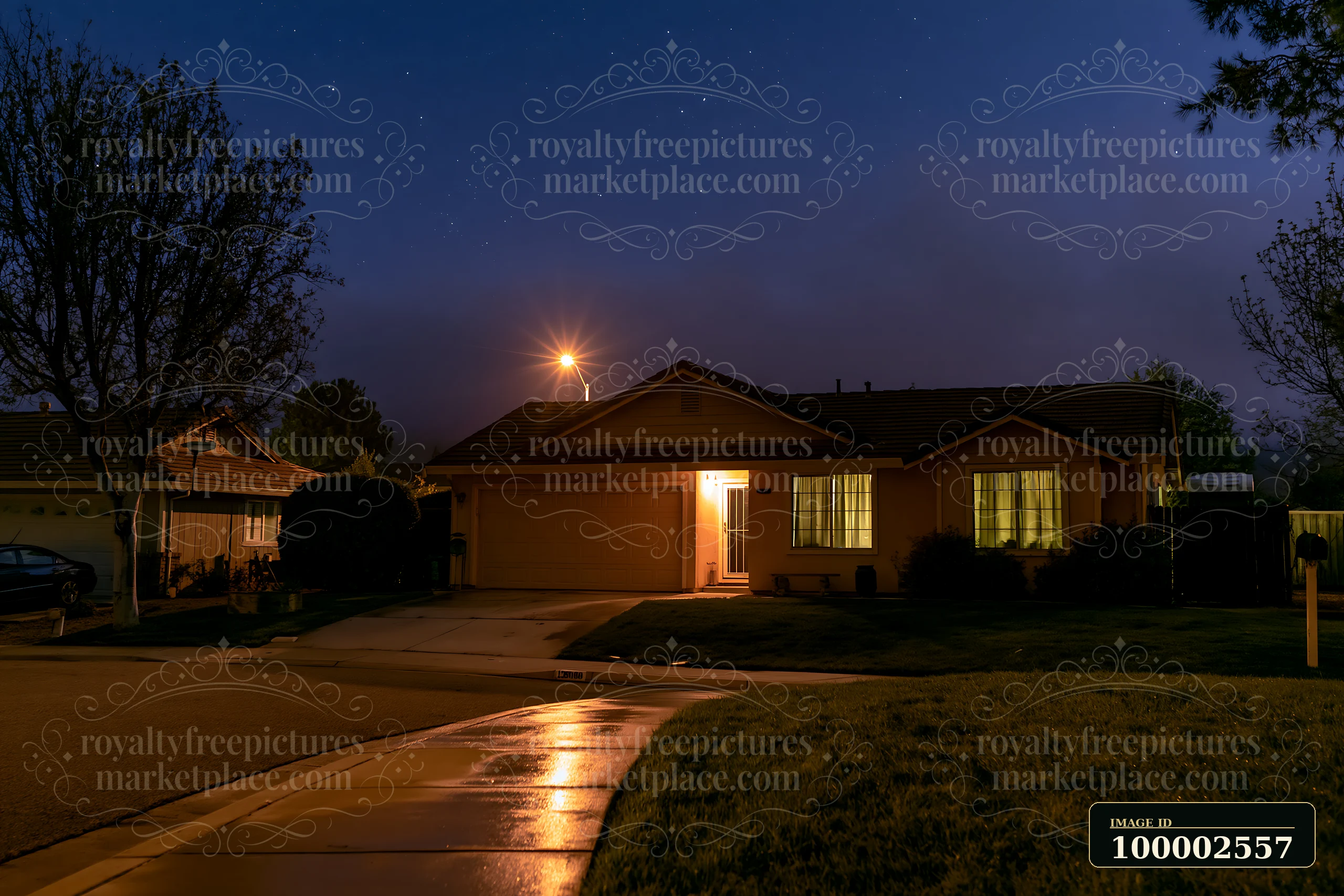 A house stands under a starry sky during the blue hour, illuminated by lights from inside.