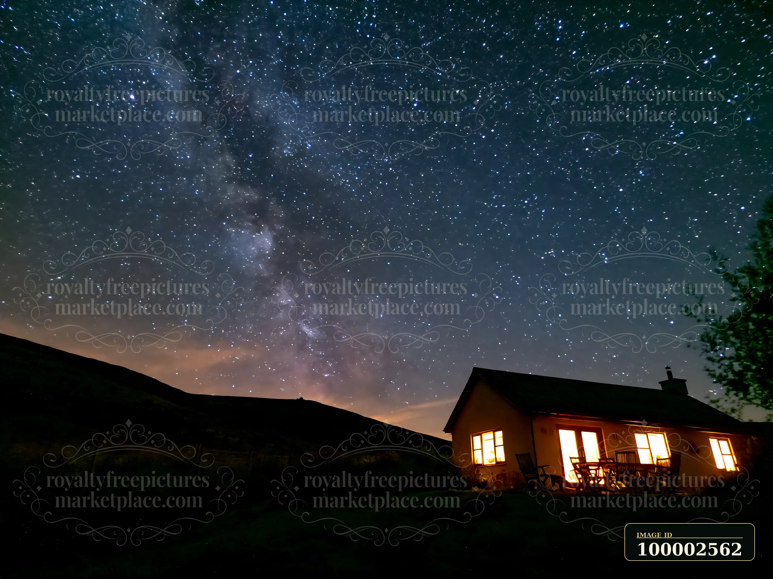 A bright modern house stands under the Milky Way as stars fill the night sky.