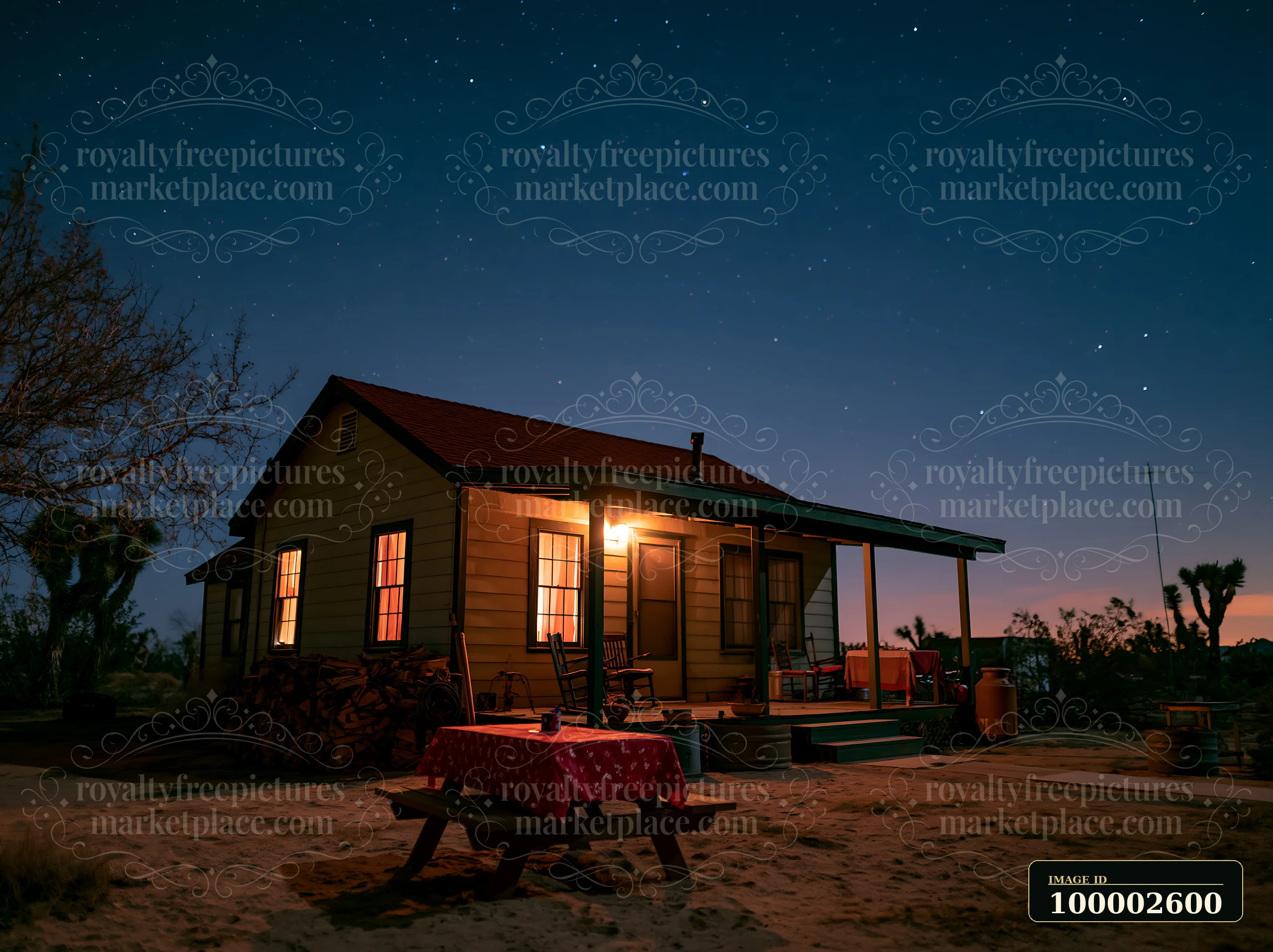 A small desert home stands under a starry sky, with warm light spilling from the windows and illuminating the porch.