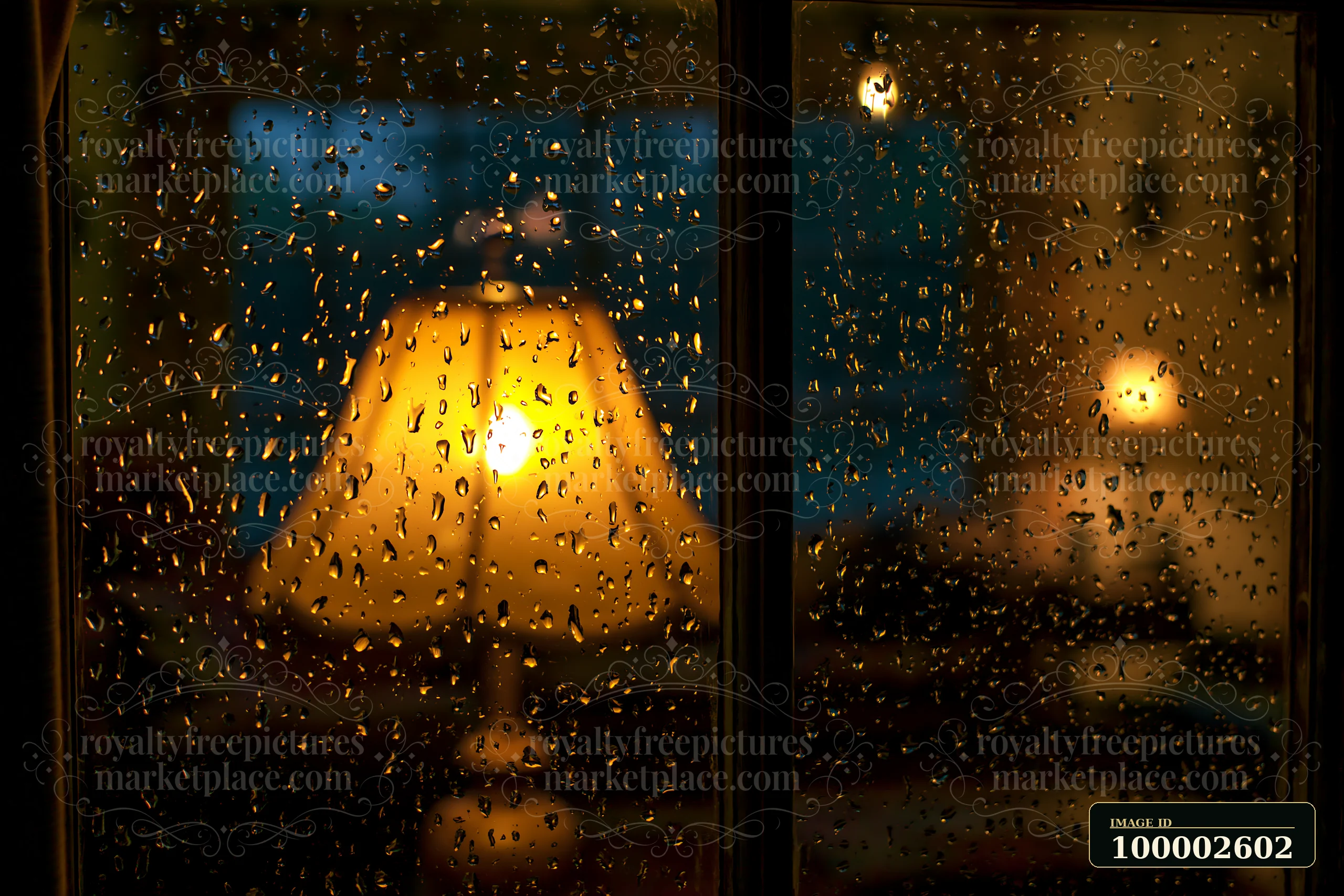 Raindrops on cottage window with warm lamp glow create a cozy atmosphere.