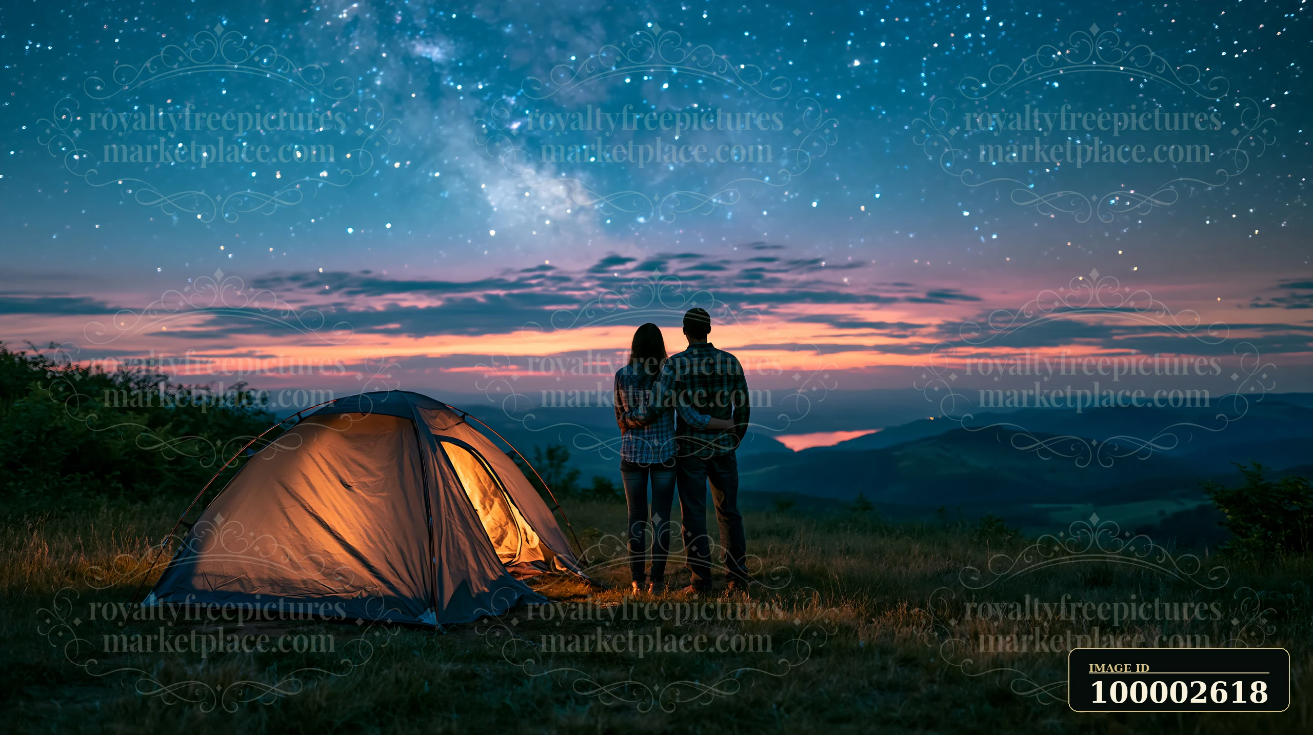 A couple stands close to each other, looking up at a star-filled sky while camping.