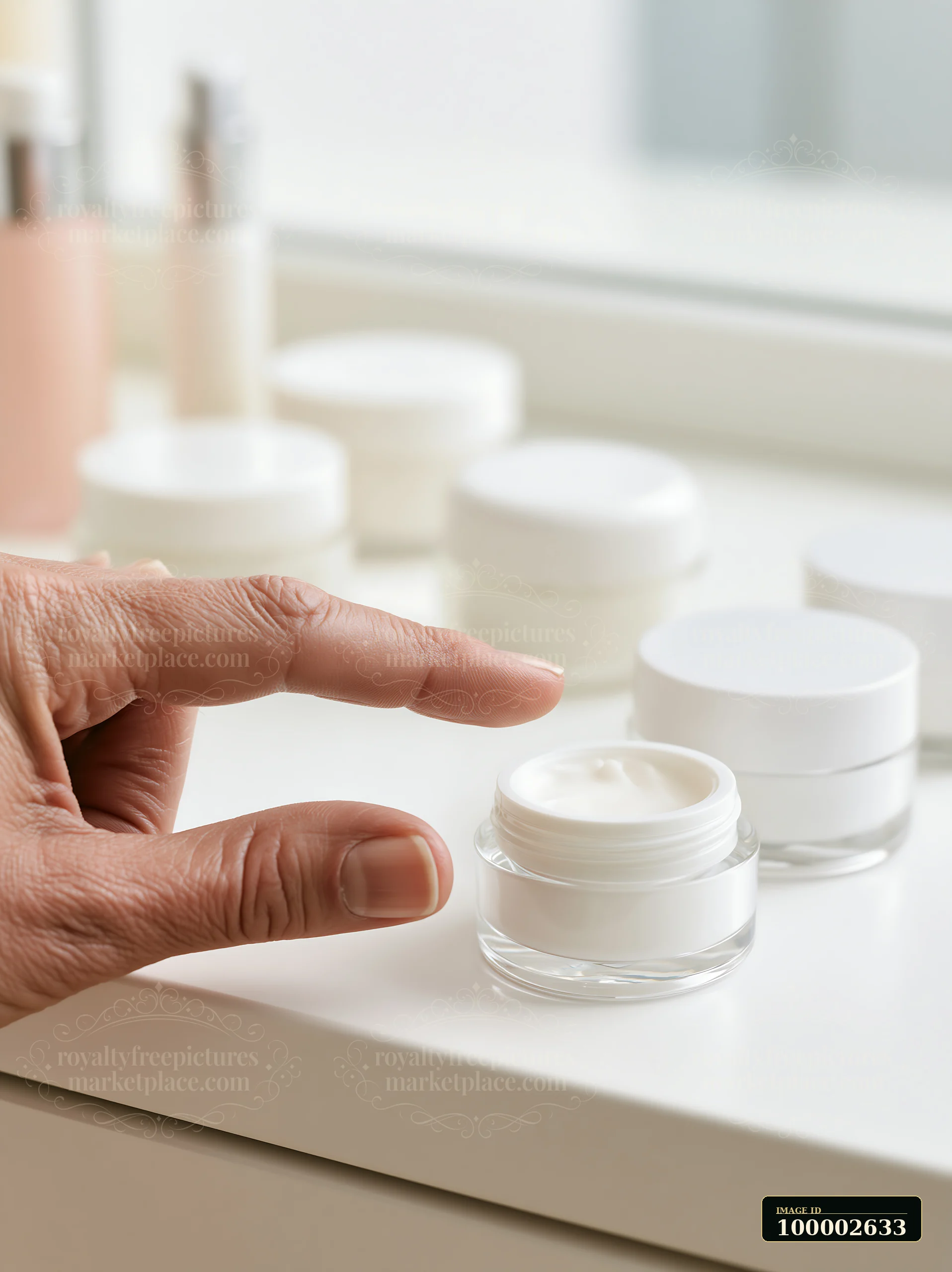 A hand is reaching for a cream dose beside unbranded cosmetic containers on a clean table near a window.