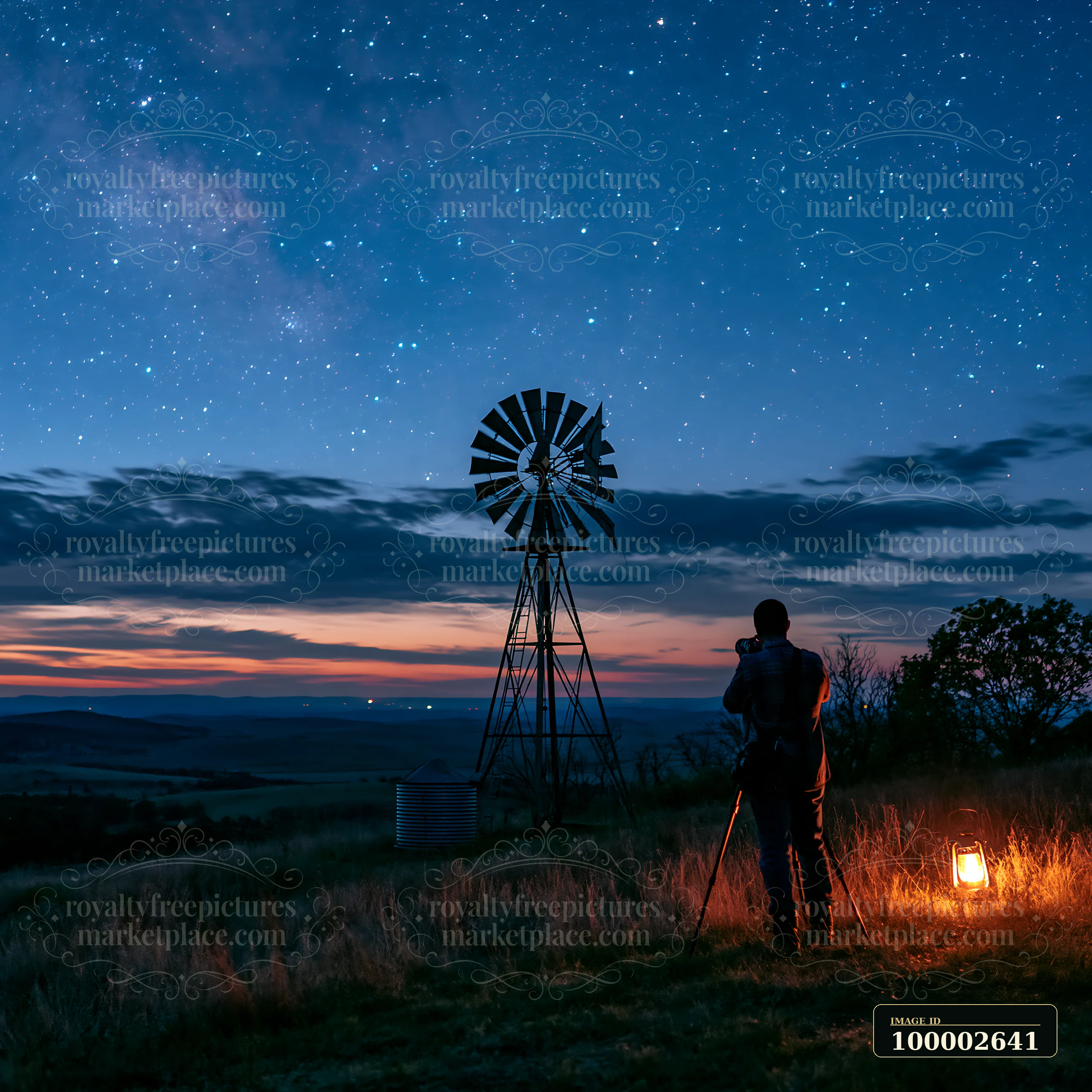 A photographer sets up a camera under the stars near a windmill as twilight fades.