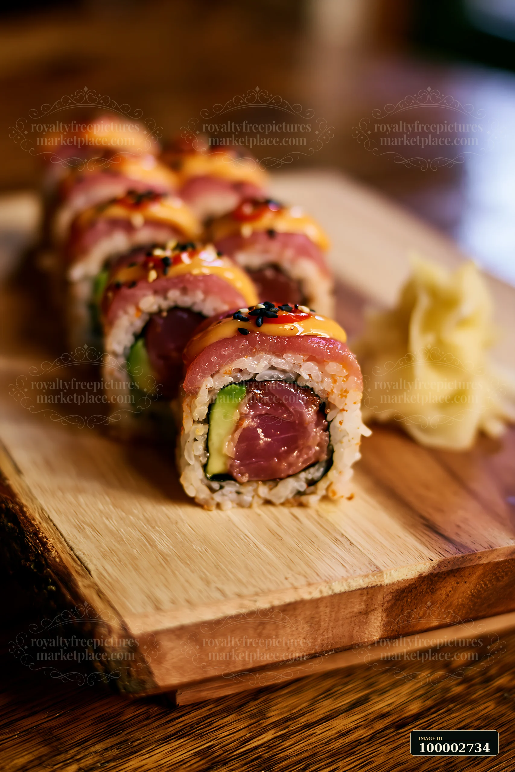 A spicy tuna roll is arranged on a wooden board with slices of tuna and avocado.