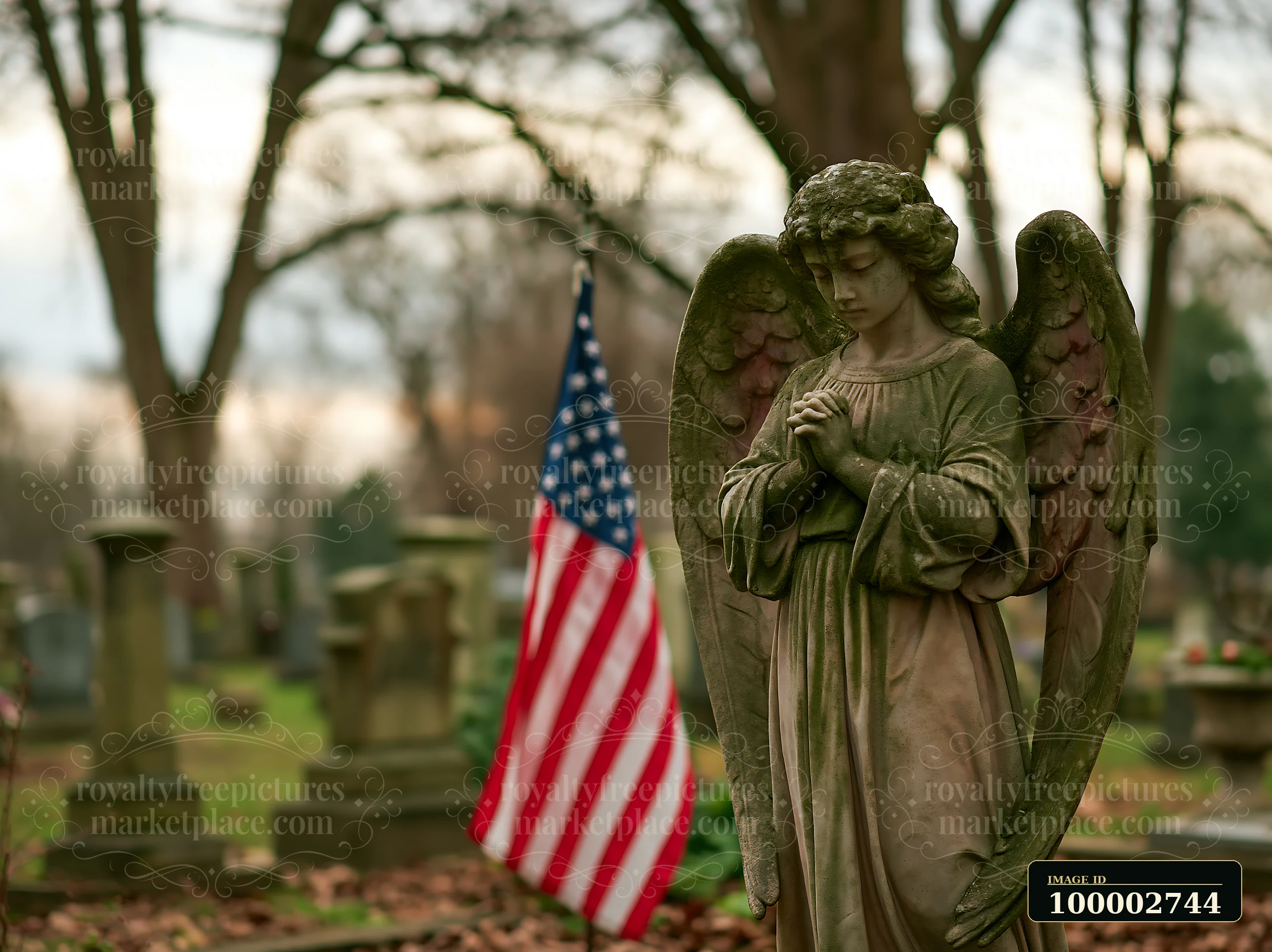 An angel statue stands with hands clasped in a cemetery, surrounded by gravestones and an American flag in the background.