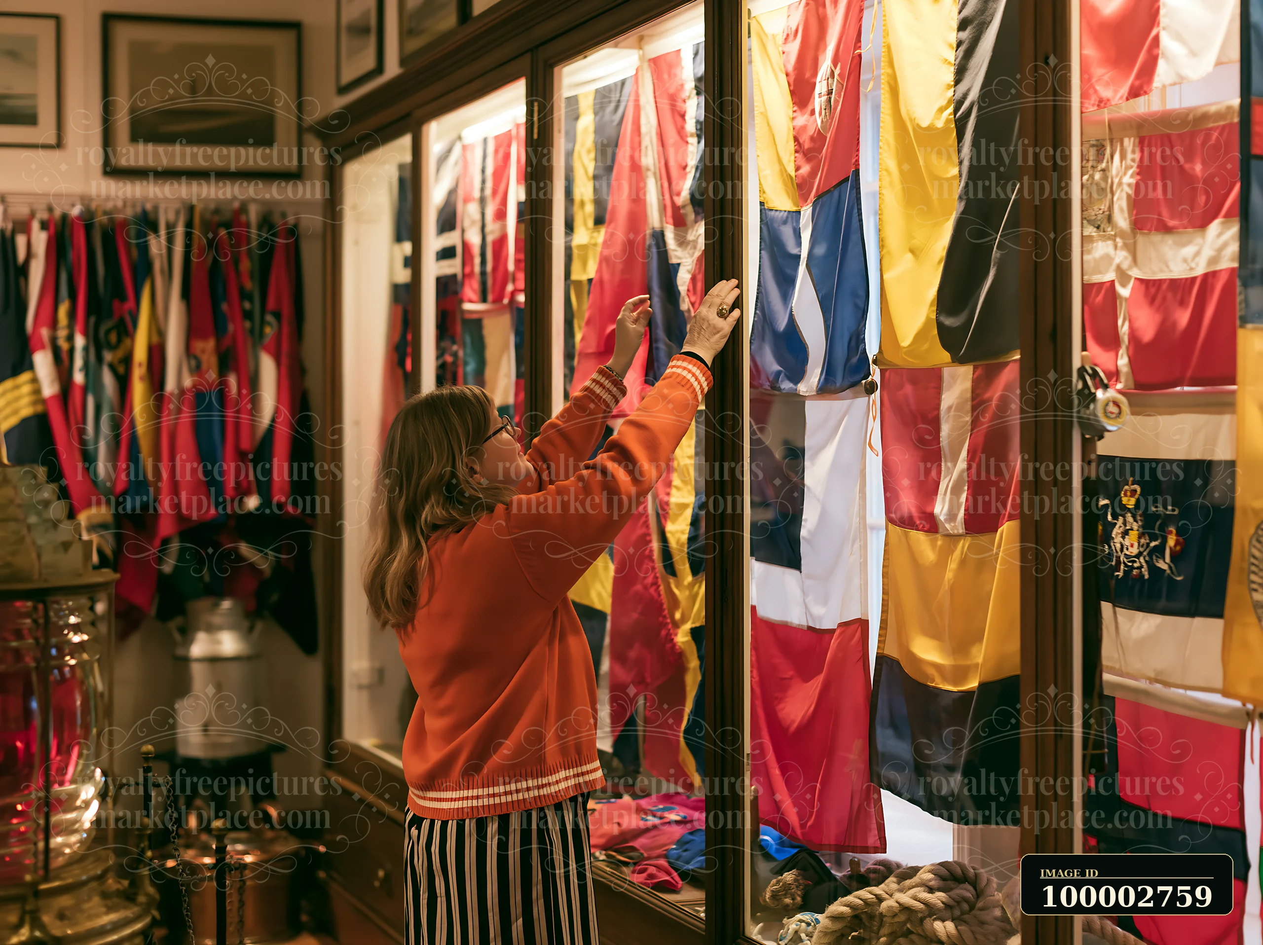 A woman examines displays of historical maritime flags inside a lighthouse museum interior, showcasing a collection of colorful flags and artifacts relevant to