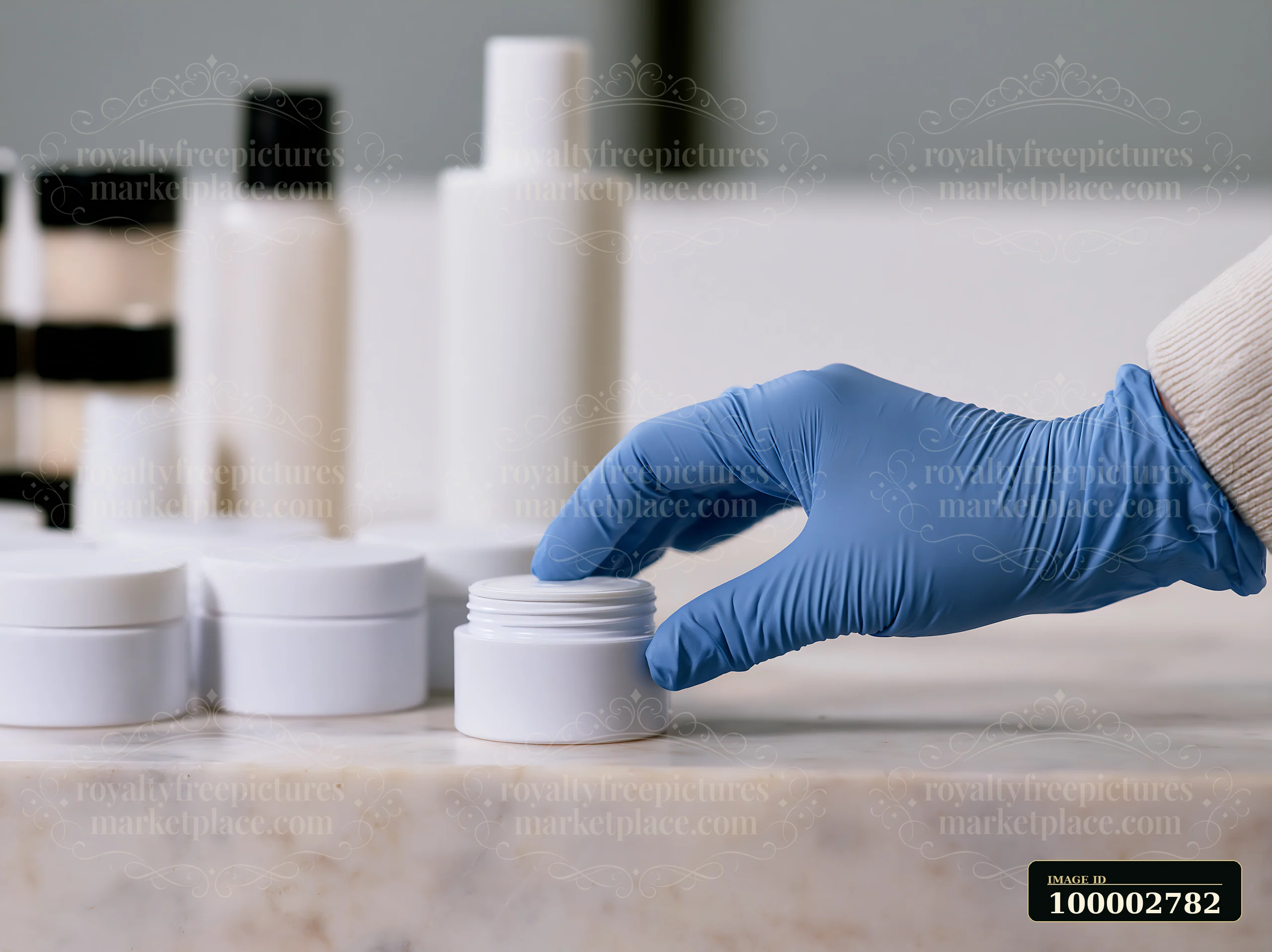 A hand wearing a blue glove reaches for a cream dose beside unbranded cosmetic containers on a tabletop.