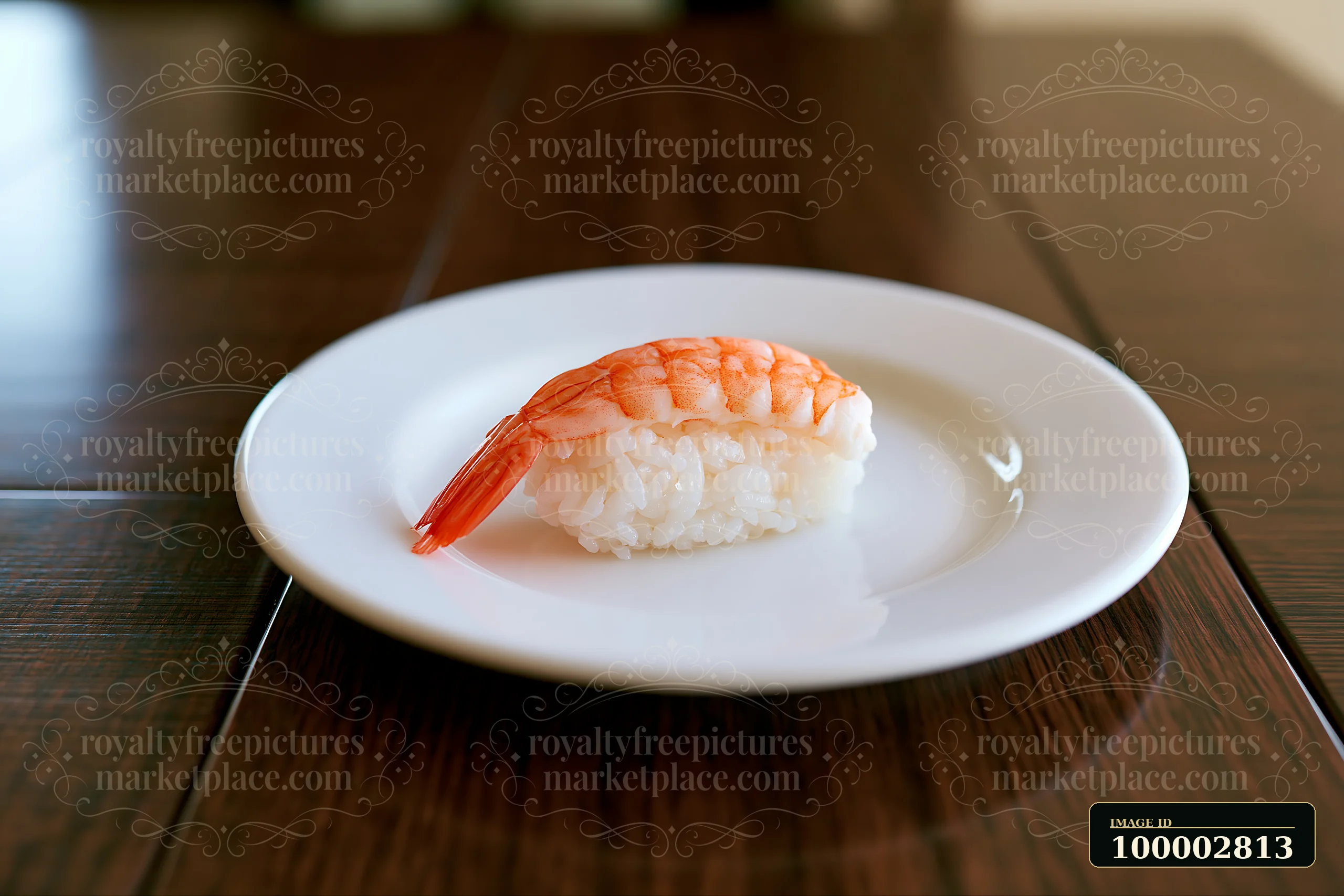 One shrimp sushi piece on white plate sits on a wooden table.