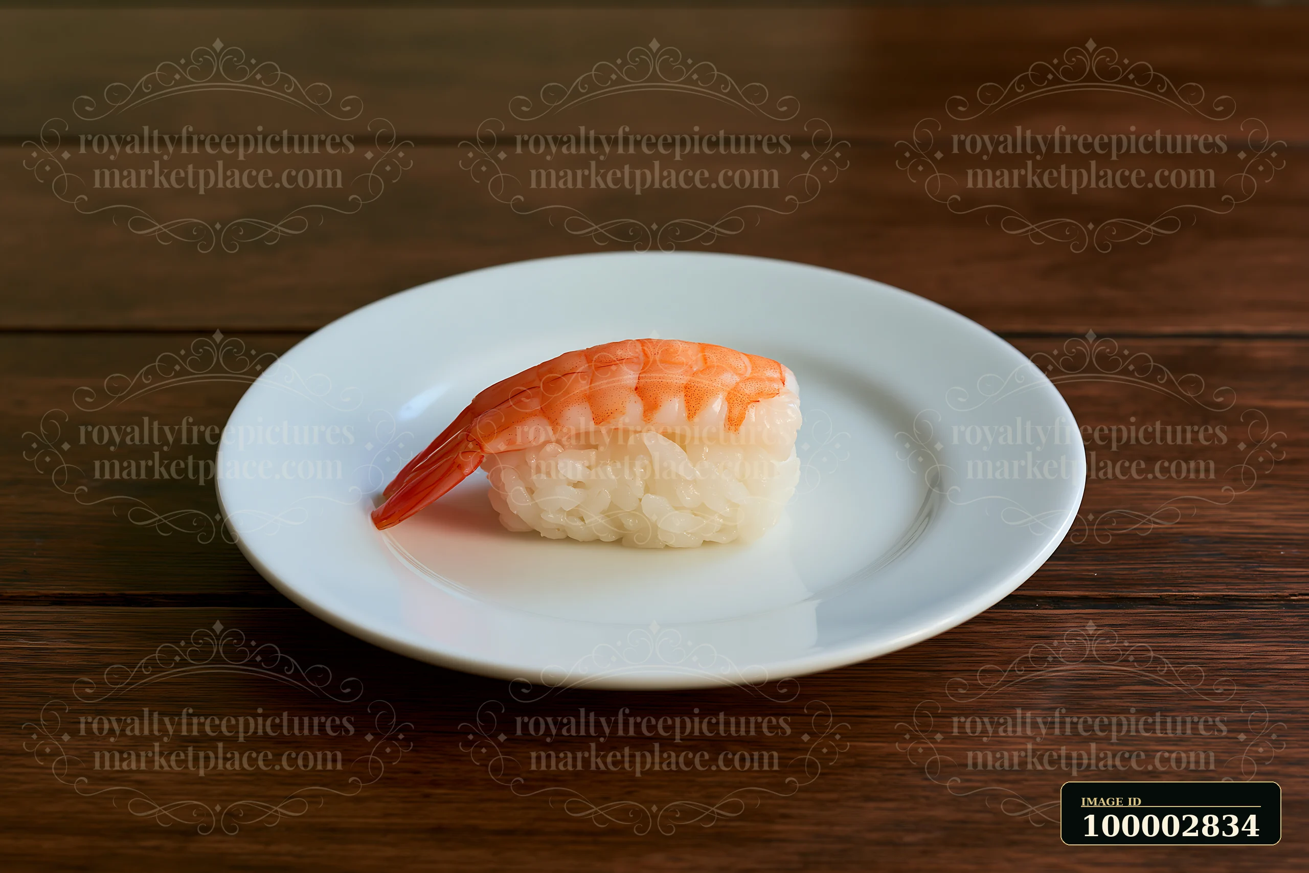 One shrimp sushi piece on a white plate sits on a wooden table.
