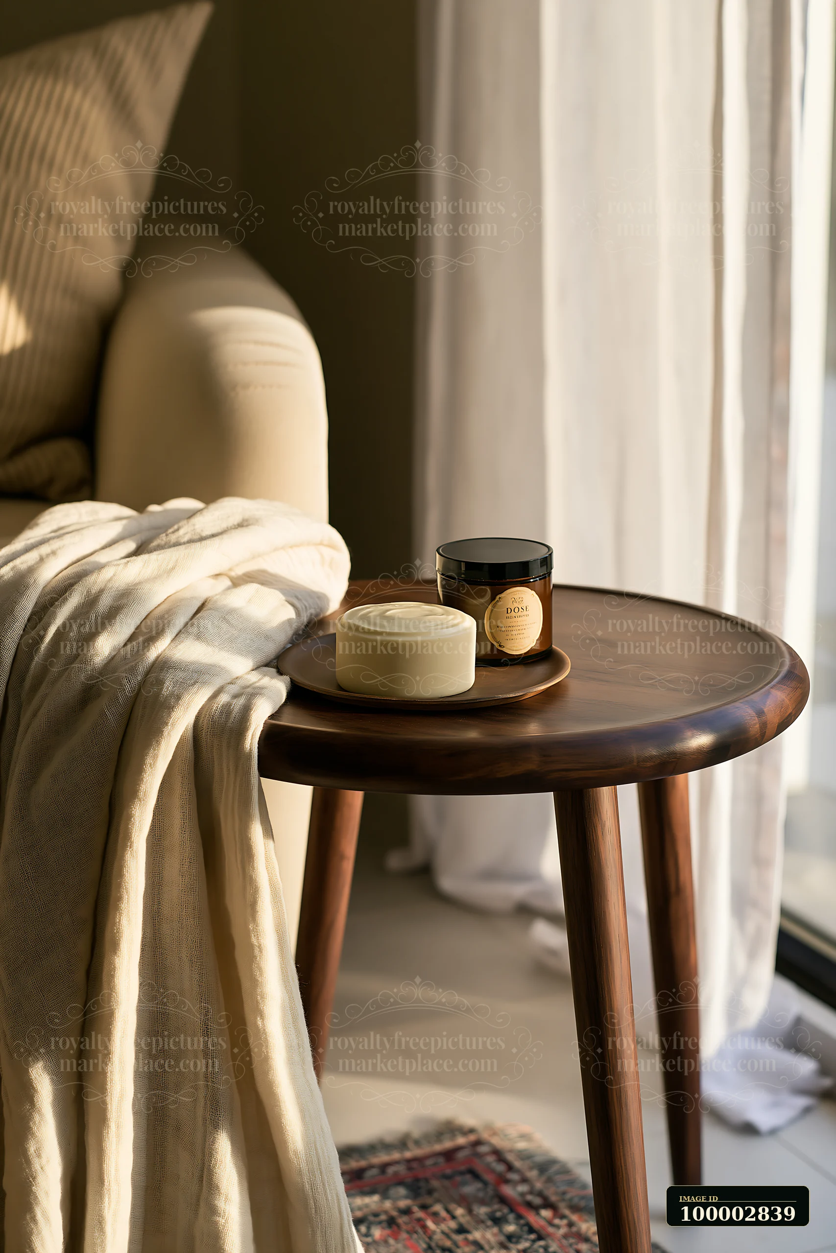A cream dose sits next to a folded robe on a wooden table in a sunlit room.